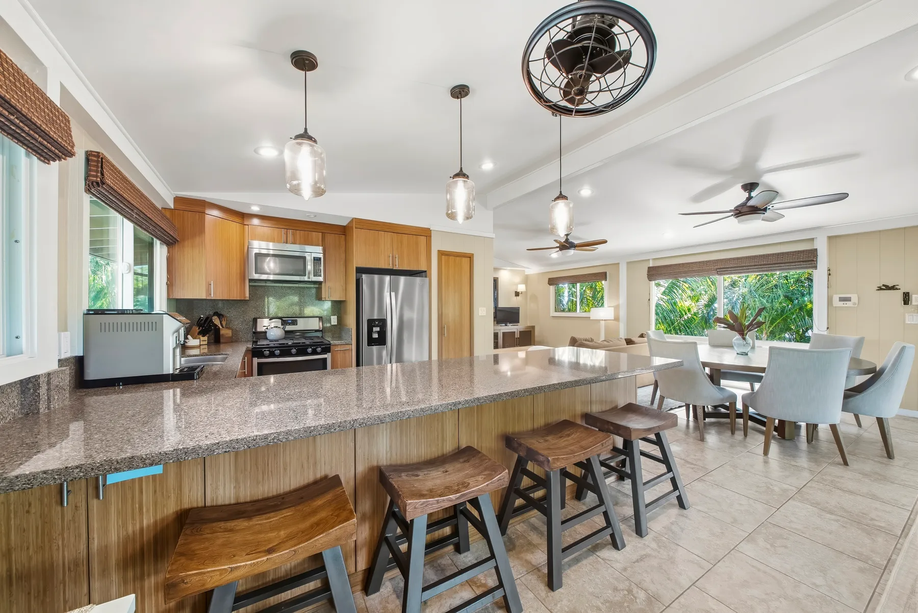Una cocina abierta y zona de comedor con una gran isla y luces colgantes.