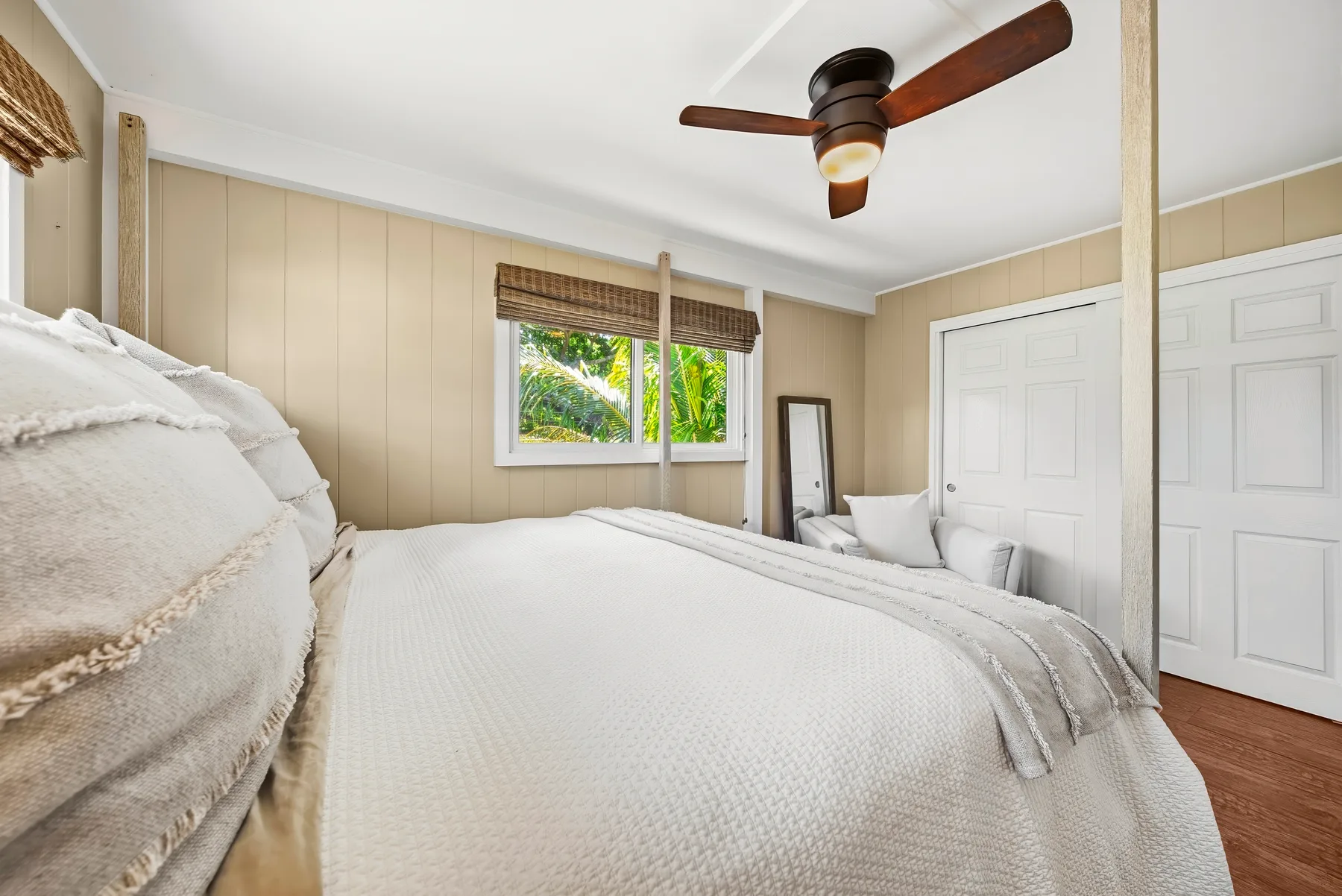 Un dormitorio luminoso con una cama grande, una ventana y un ventilador de techo.