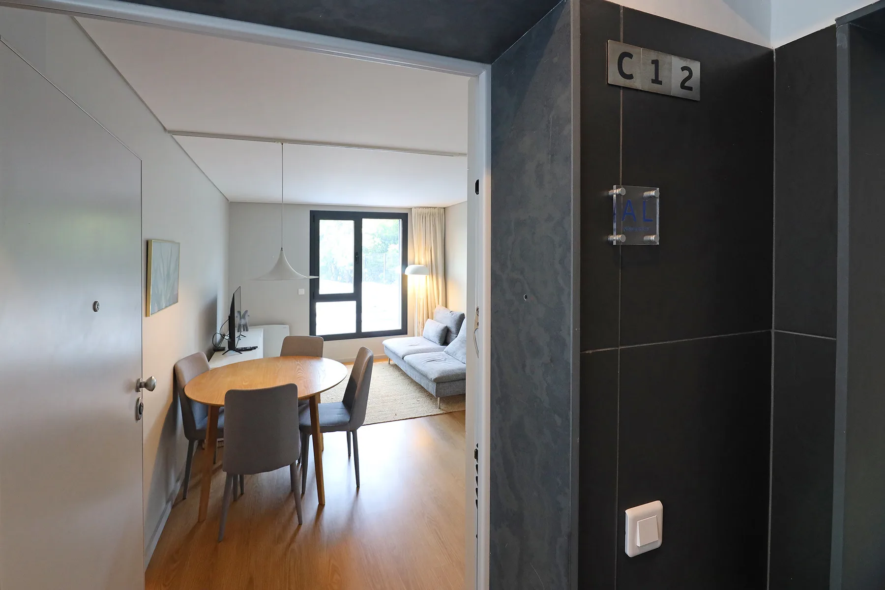 An apartment dining and living area with a table, seating, and large windows.
