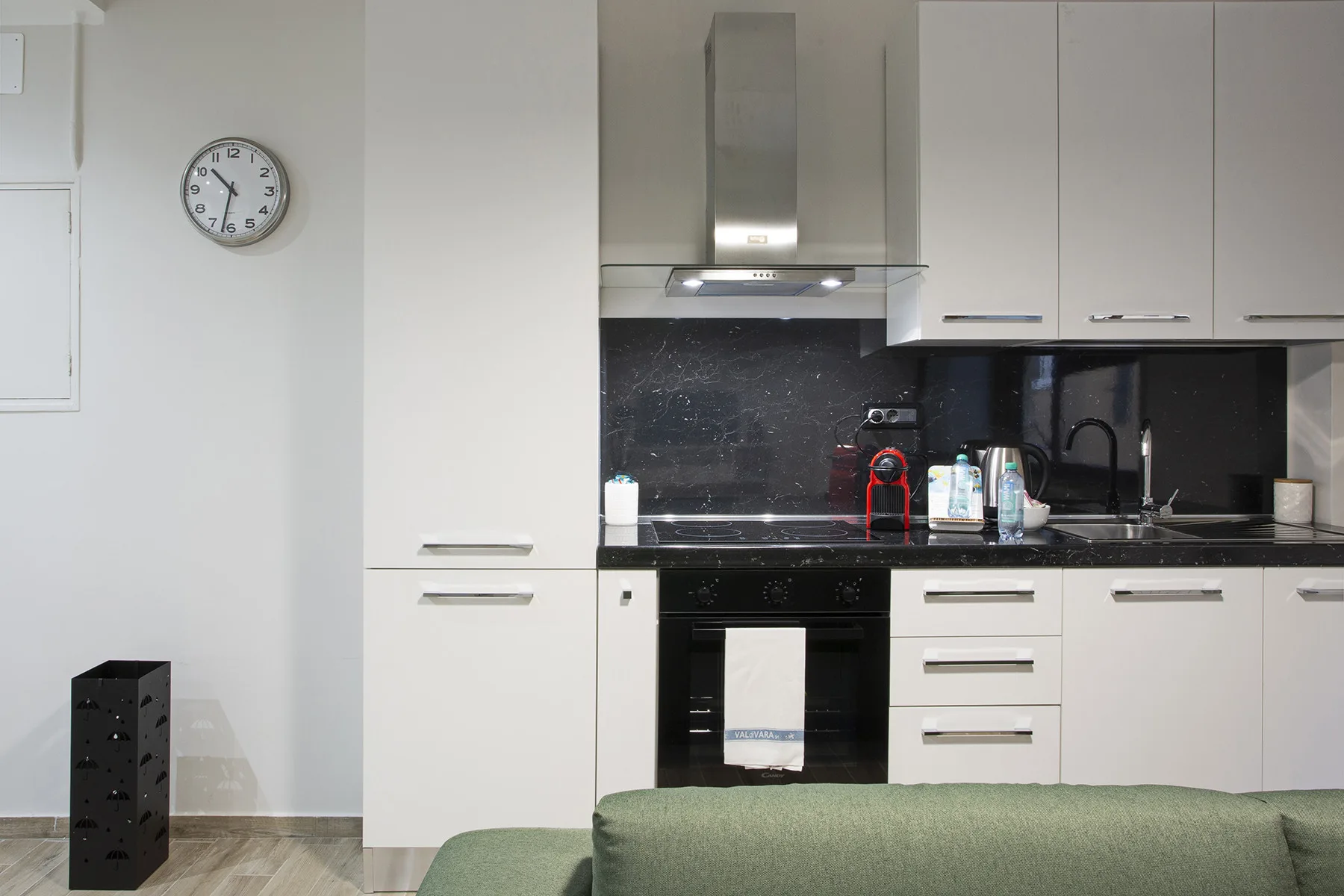 A modern kitchen with white cabinets, a dark backsplash, and a built-in oven.