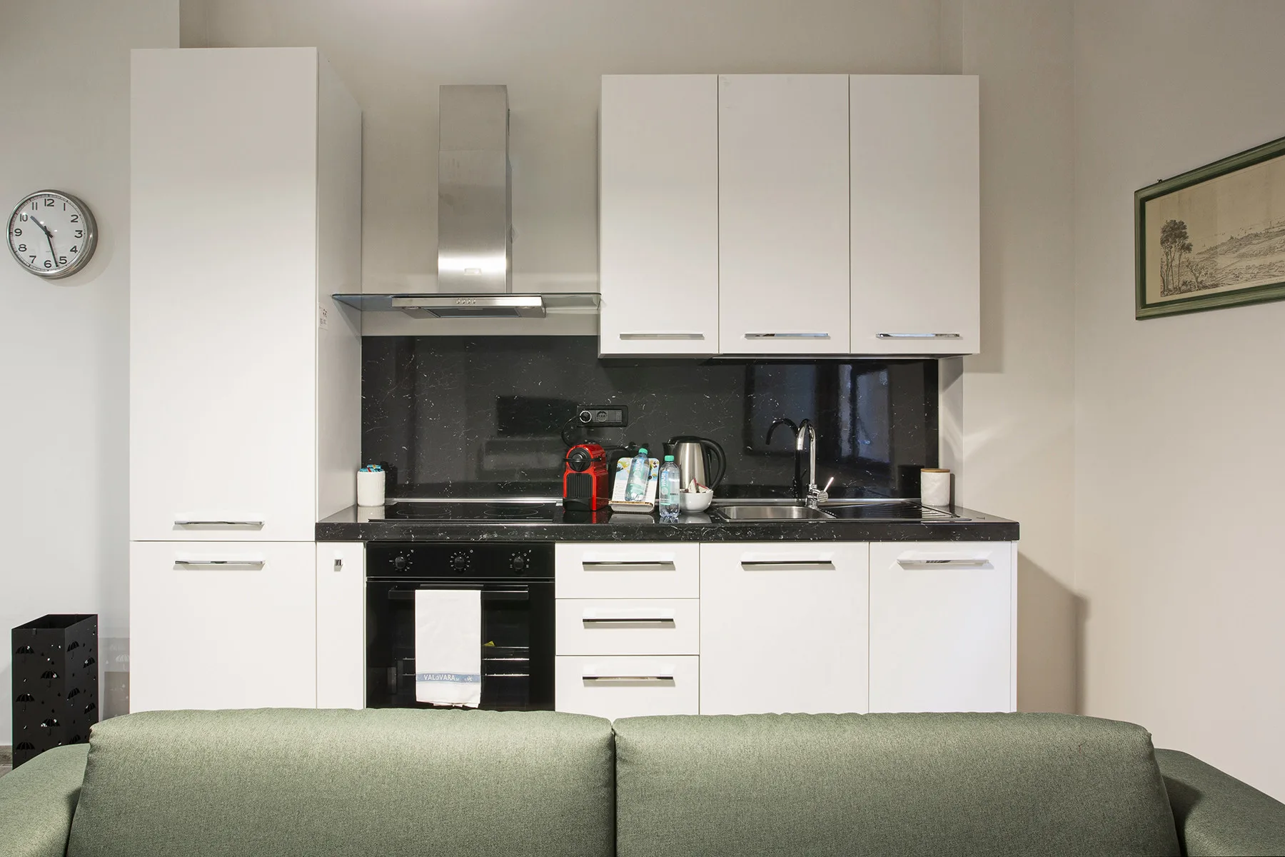 A compact kitchen with white cabinets, a dark countertop, and a sink.
