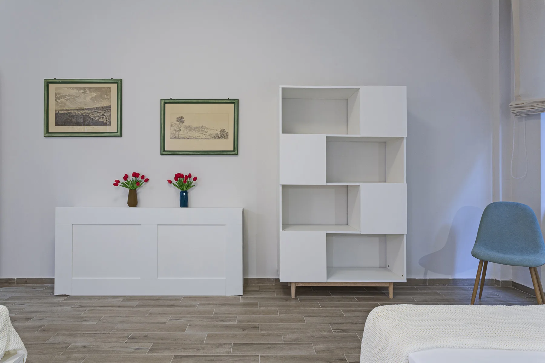 A bright living room with a white cabinet and open shelving against the wall.