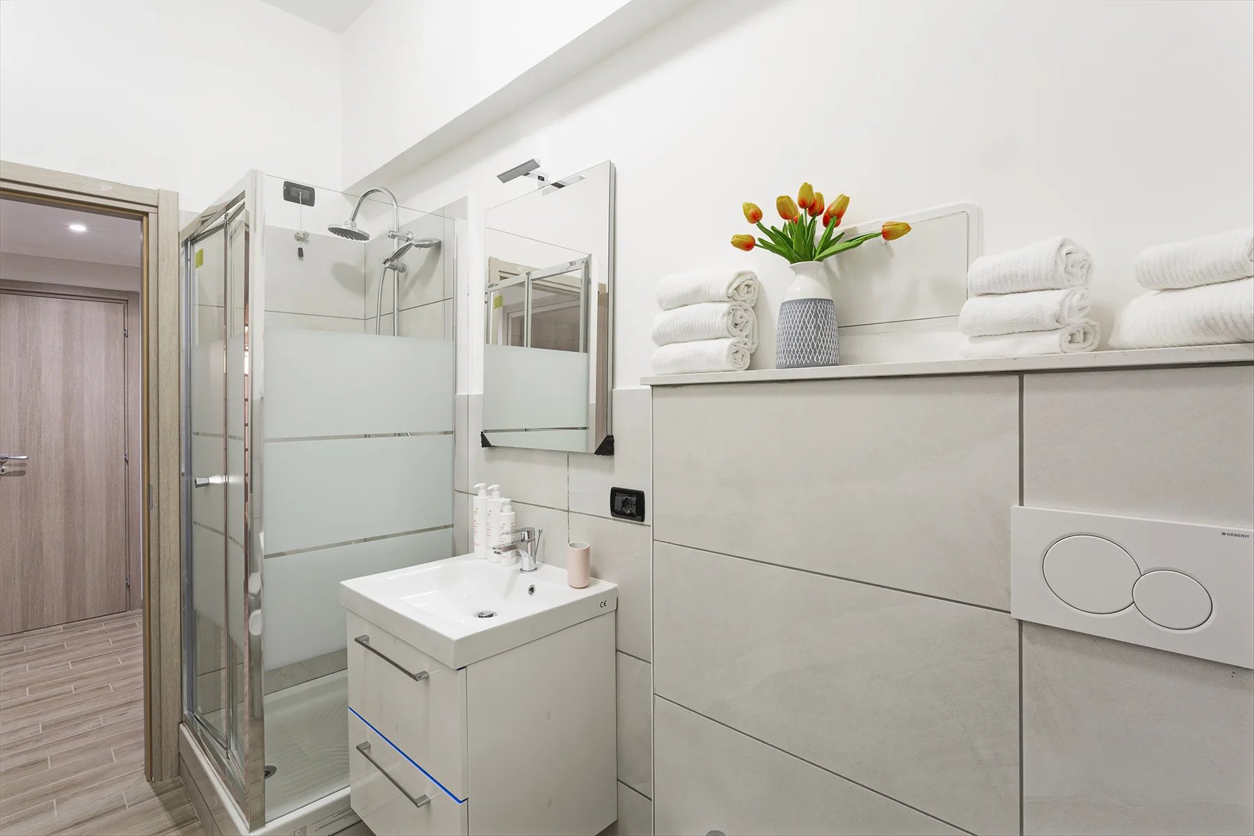 A bright bathroom with a glass shower and a sink beneath a mirror.