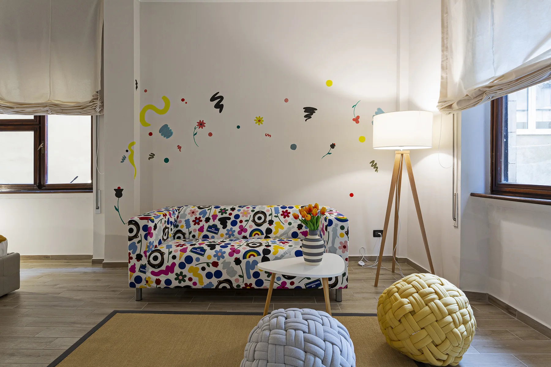 A bright living room with colorful patterned seating and playful wall decorations.