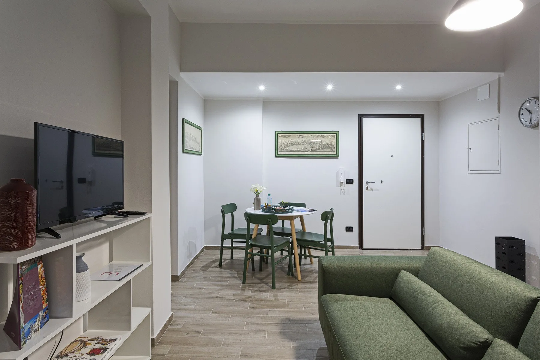 A living area with a green sofa, television, and dining table.