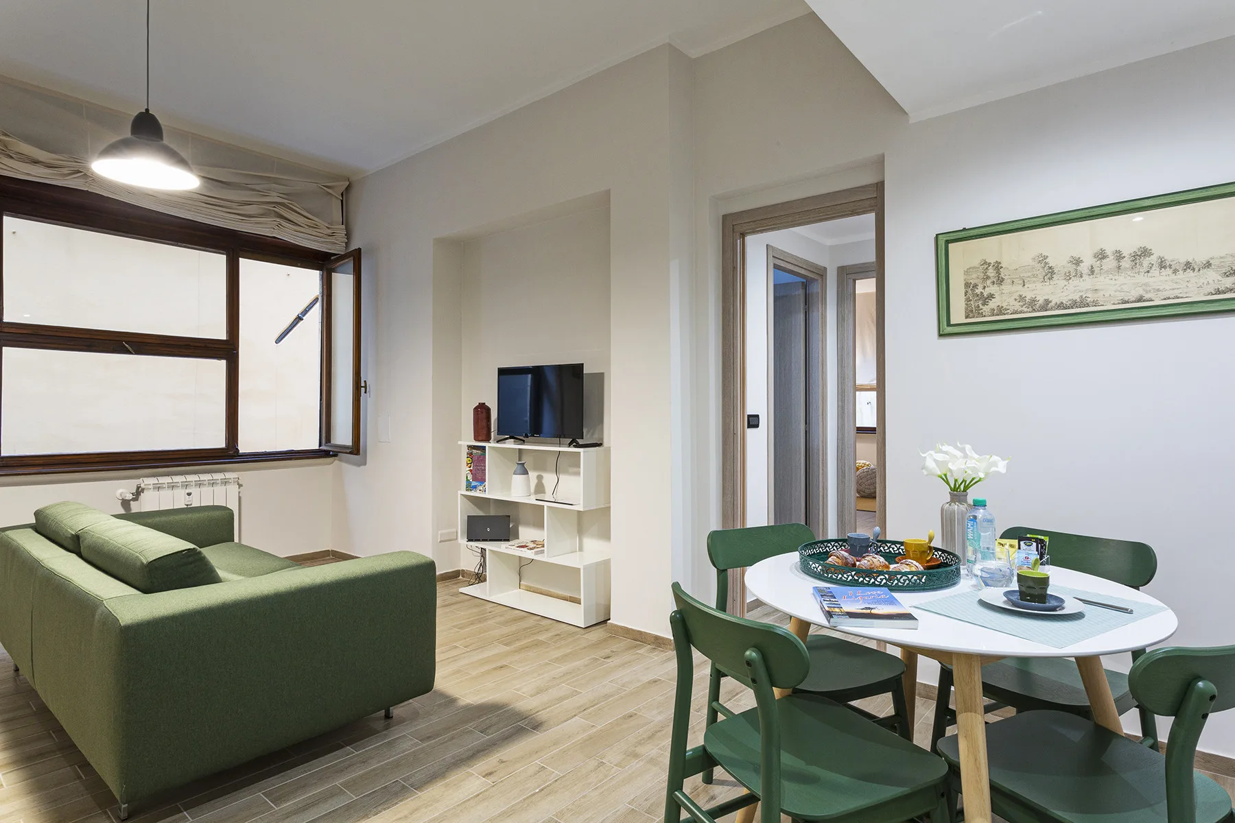 A living and dining area with green seating, a television, and a set table.