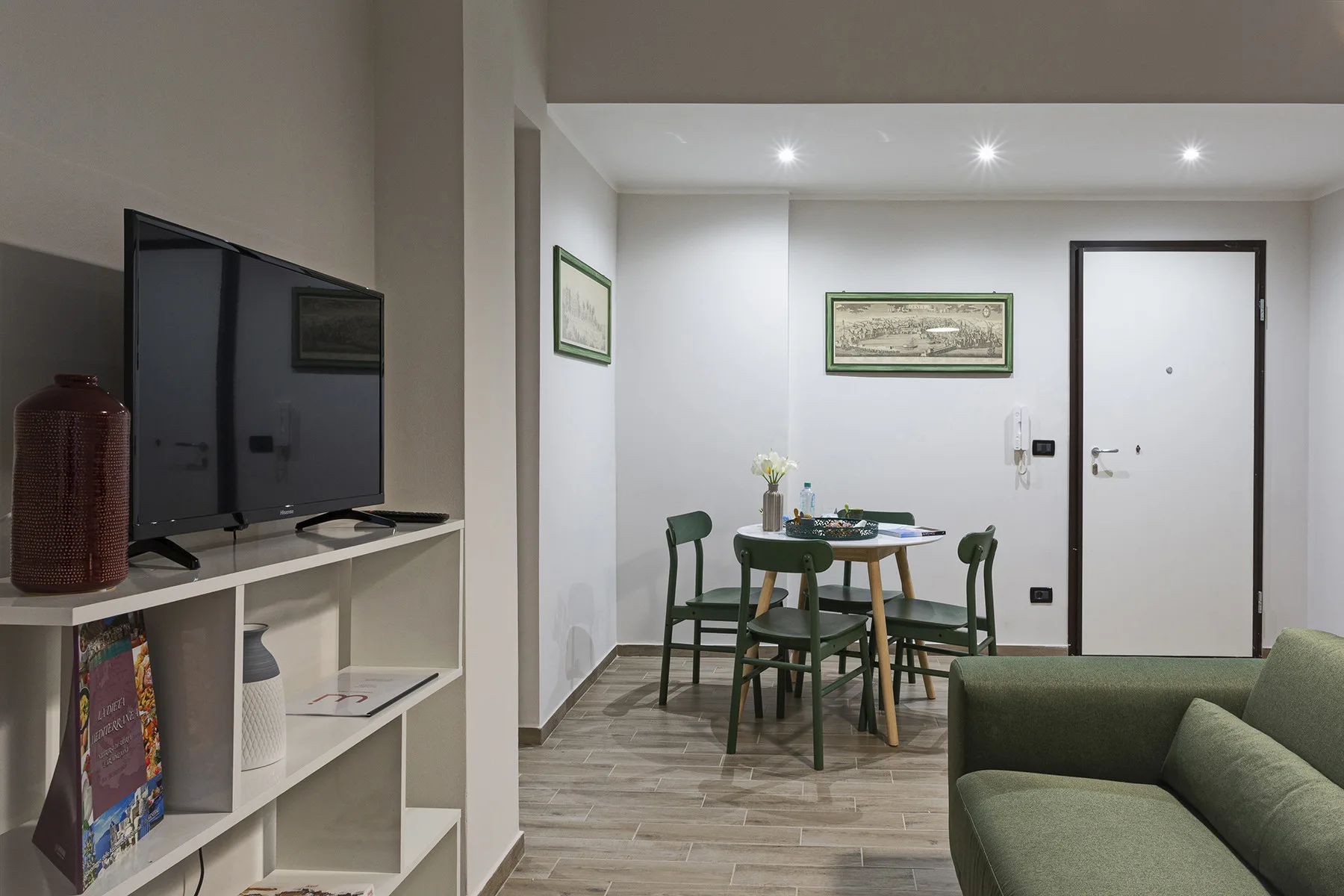 A dining area with a round table and green seating beside a living area.