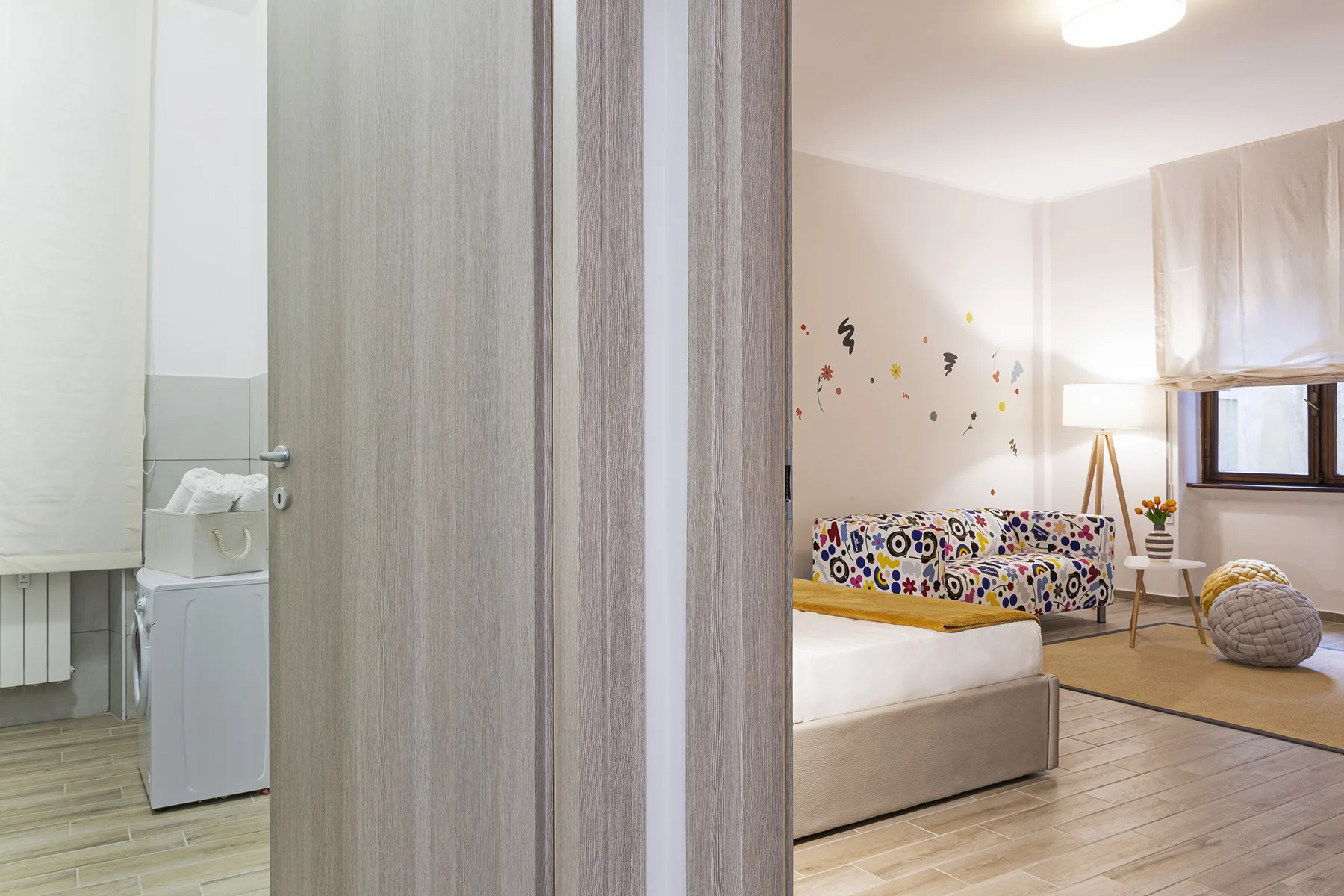 A bedroom with a bed, patterned bedding, and a window.