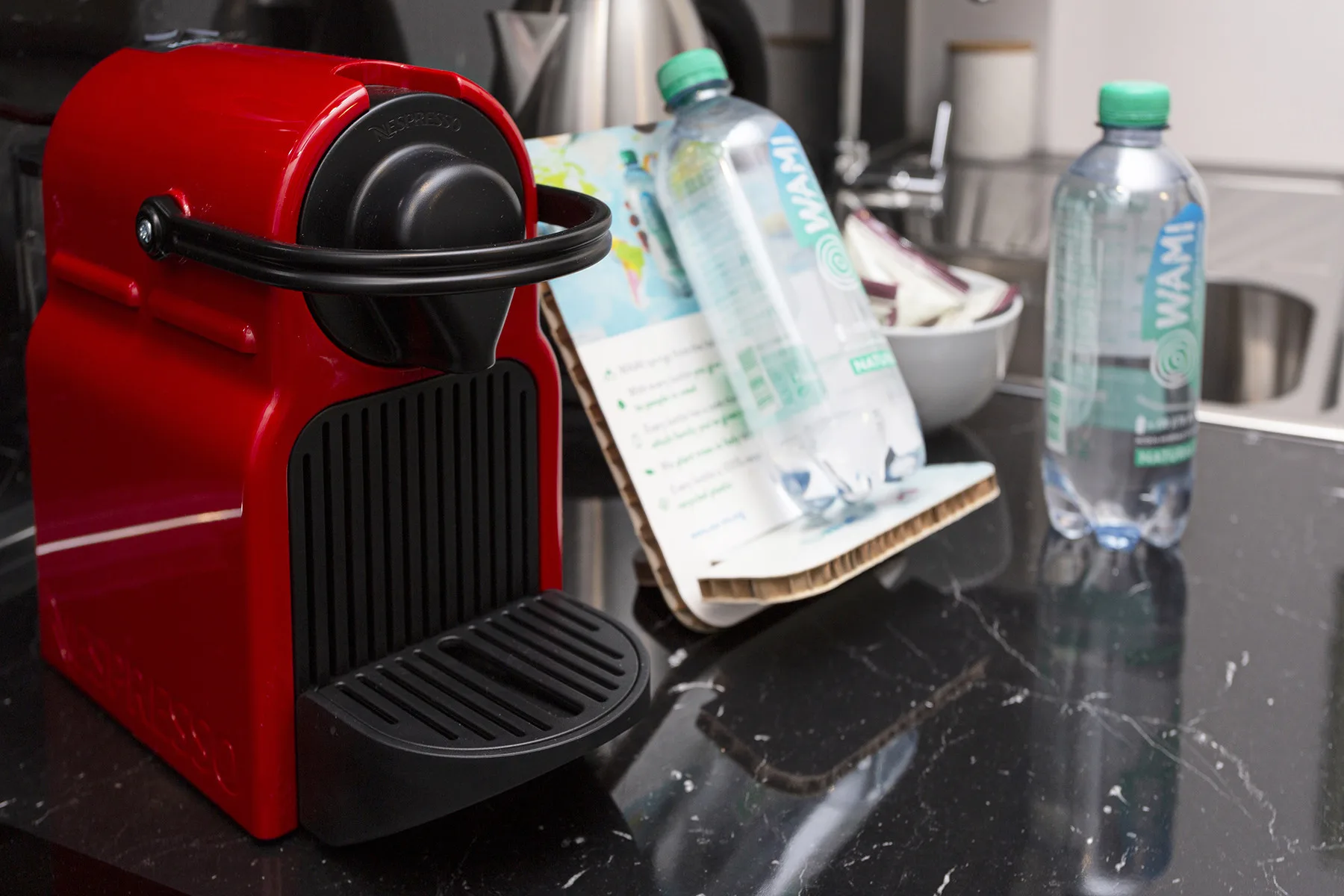 A red coffee machine and bottled water sit on a kitchen counter.