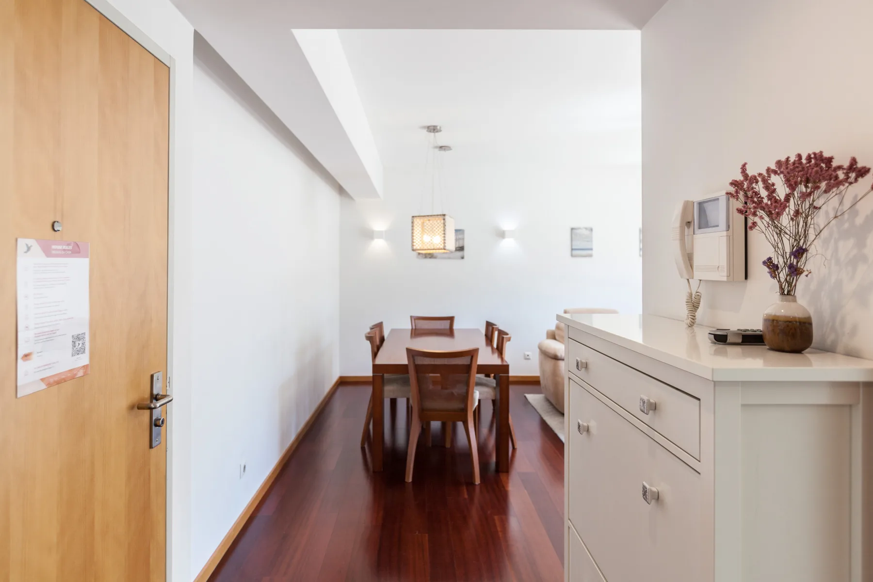 A dining area with a wooden table and chairs beside a white cabinet.