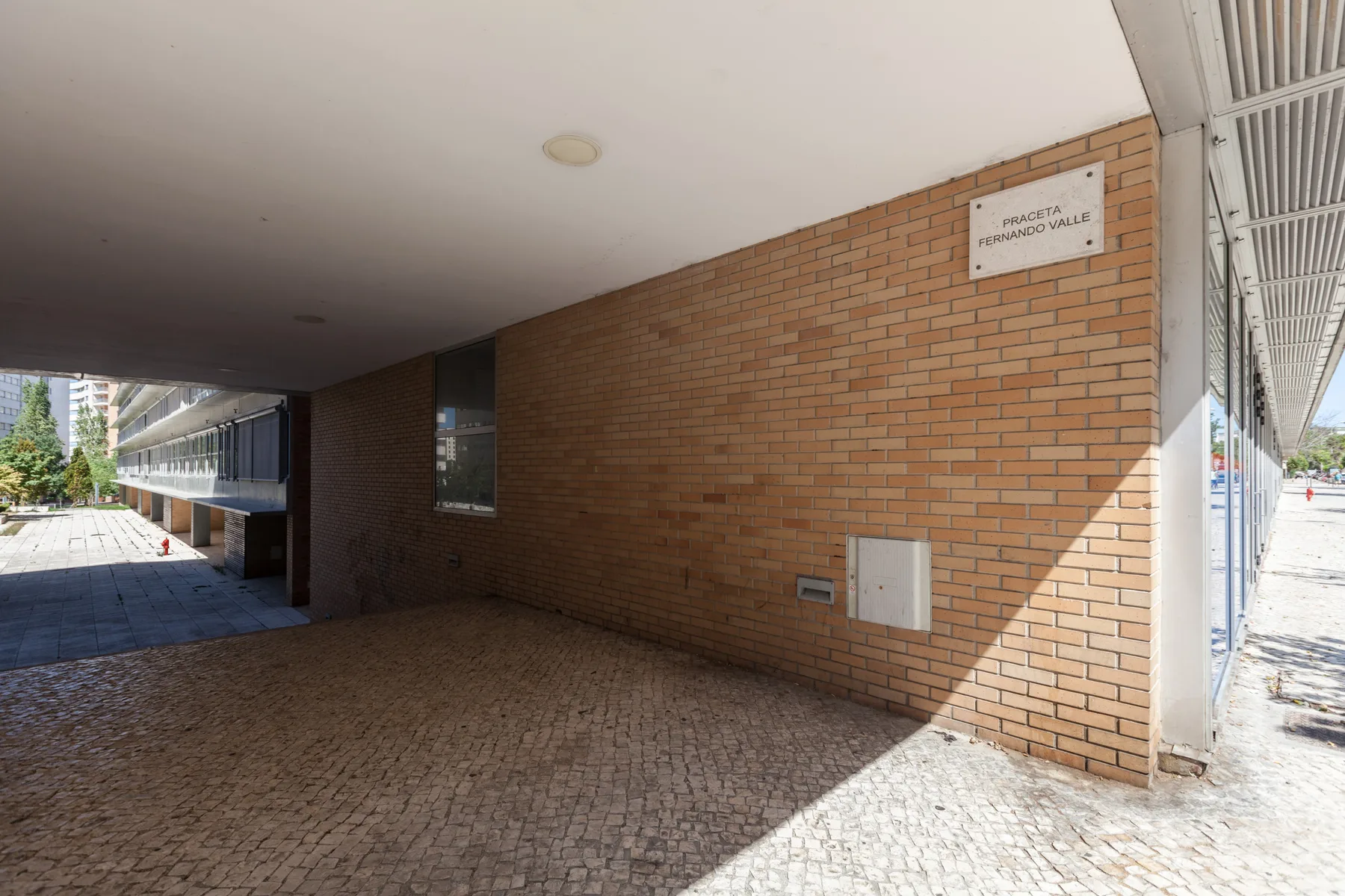A covered brick passage with cobblestone paving and a bright opening at the far end.