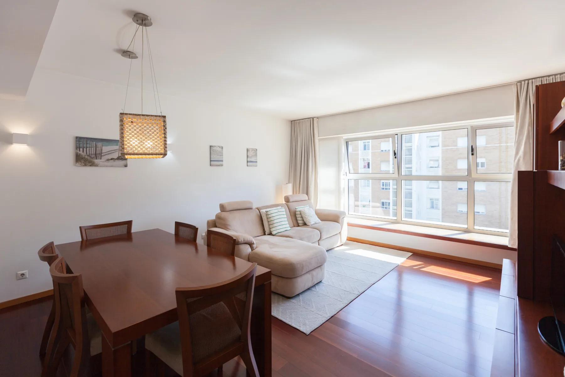 A bright living and dining area with a seating area beside large windows.