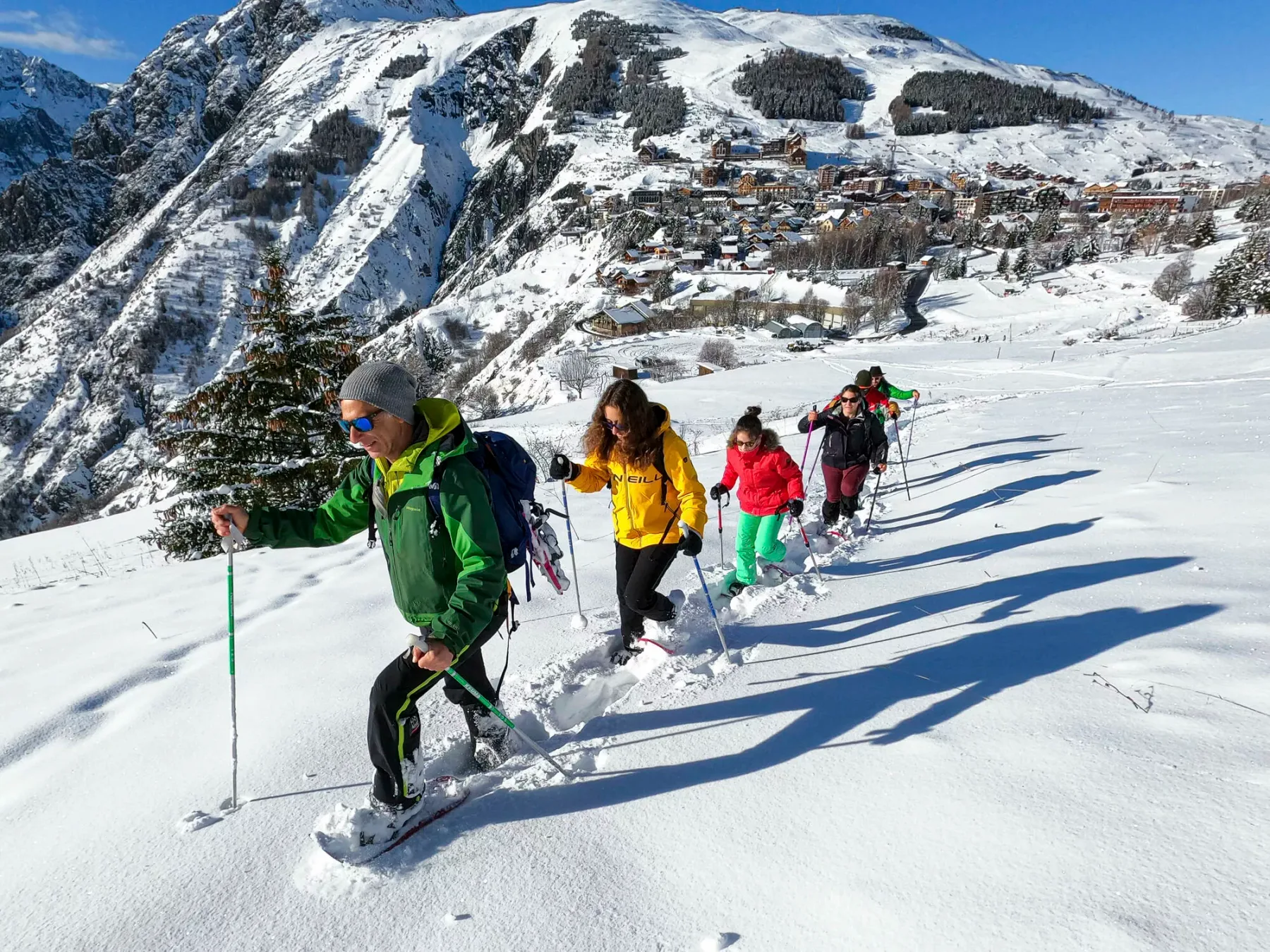 Un grupo camina cuesta arriba por la nieve en una ladera de montaña.