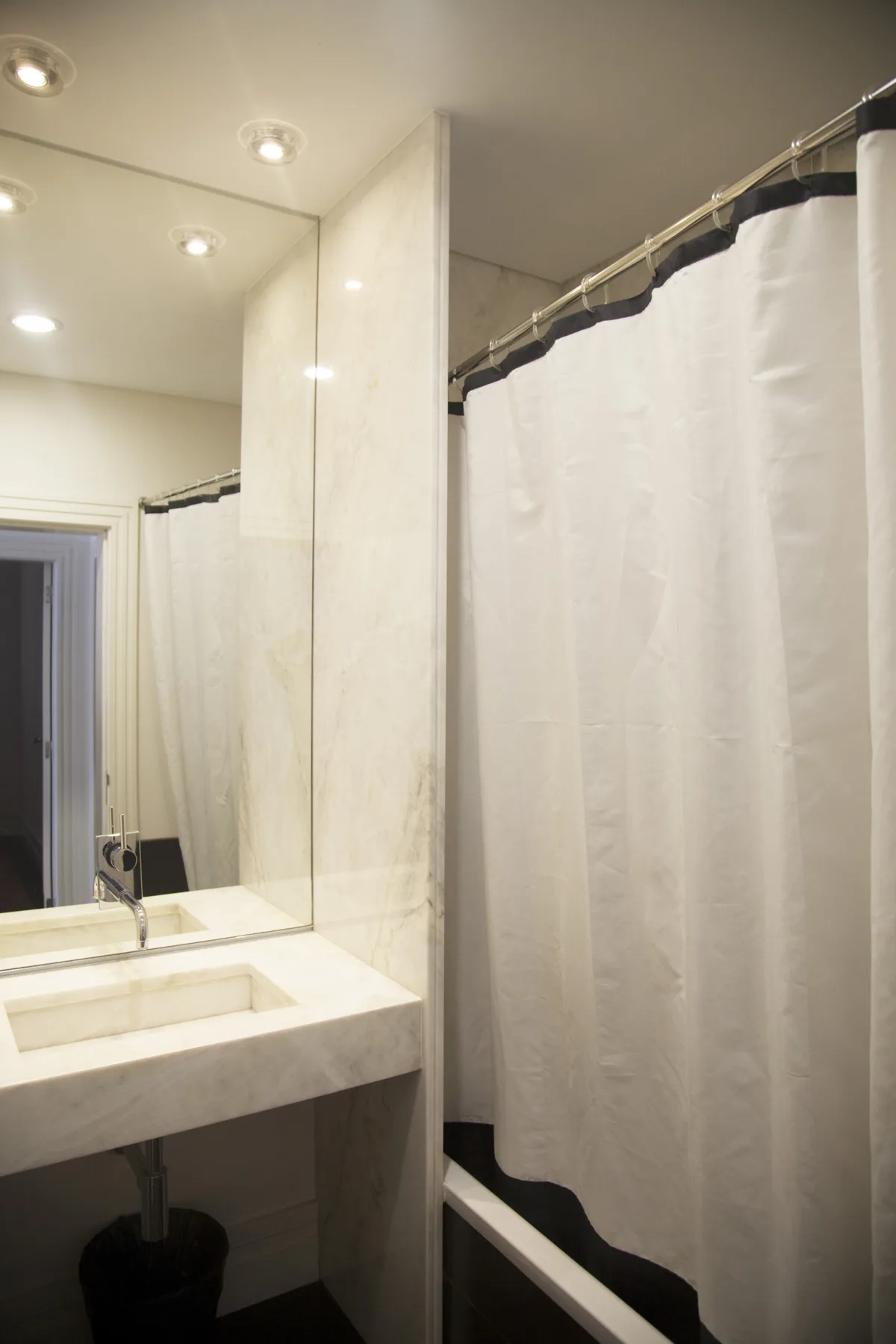 A bathroom with a sink, large mirror, and shower curtain.