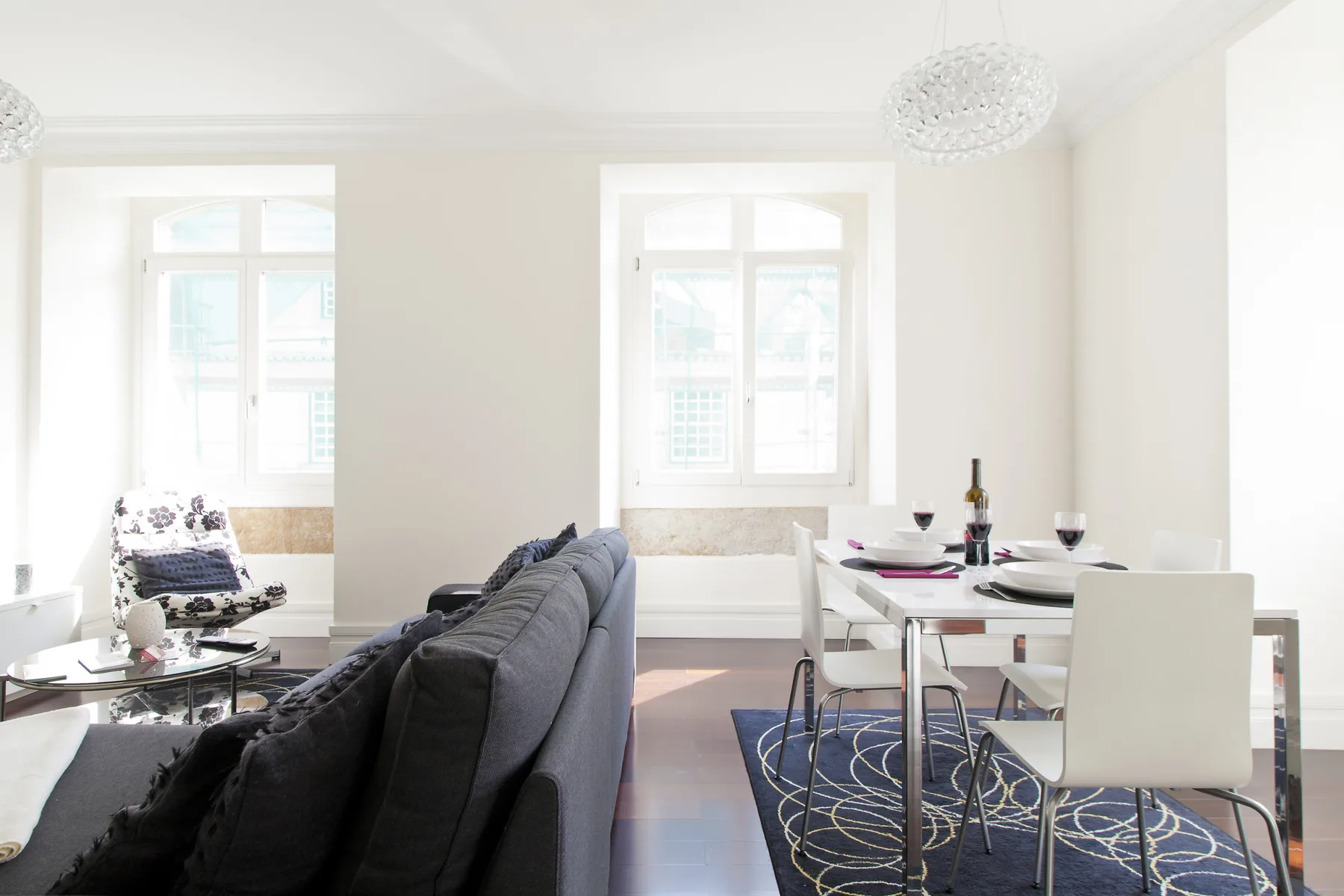 A bright living and dining room with seating, a table, and large windows.