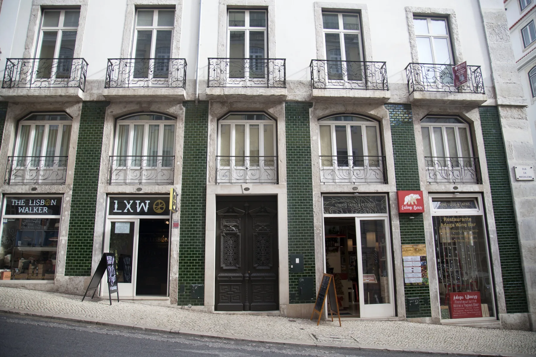 A street-level view of a building façade with balconies and storefronts.