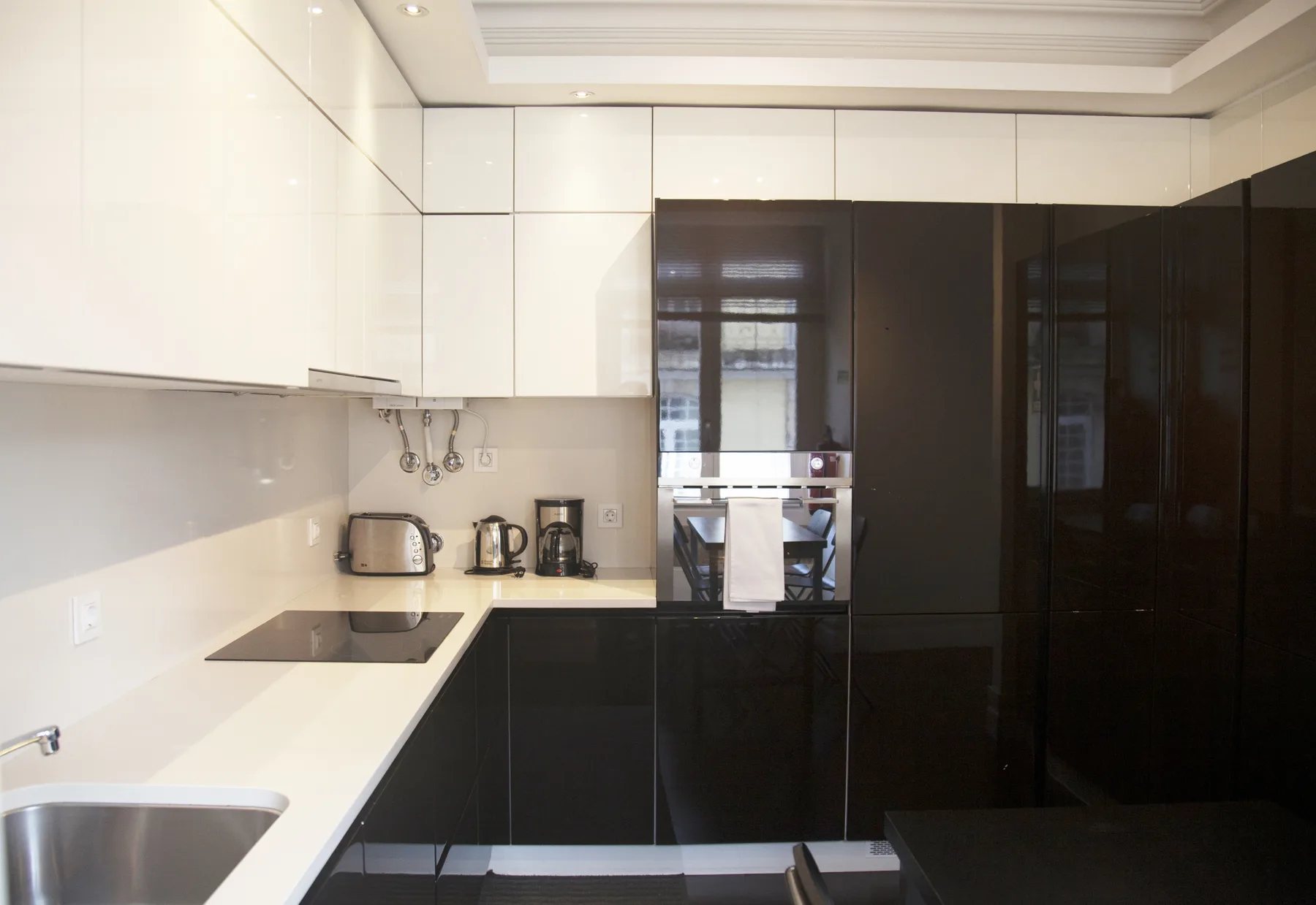 A modern kitchen with white cabinets, dark lower cabinets, and a built-in oven.