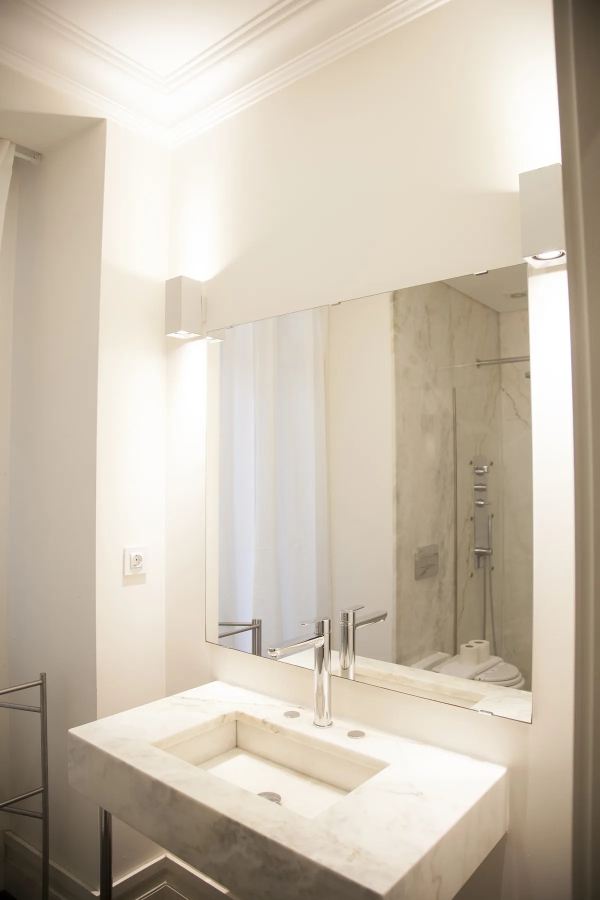 A bathroom vanity with a rectangular basin and a large mirror above it.