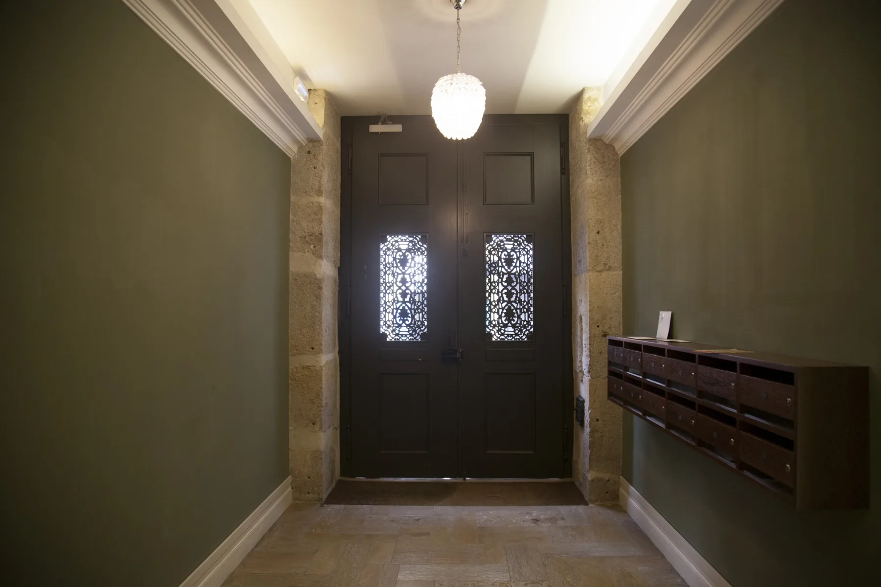 An apartment entryway with dark double doors and a row of mailboxes.