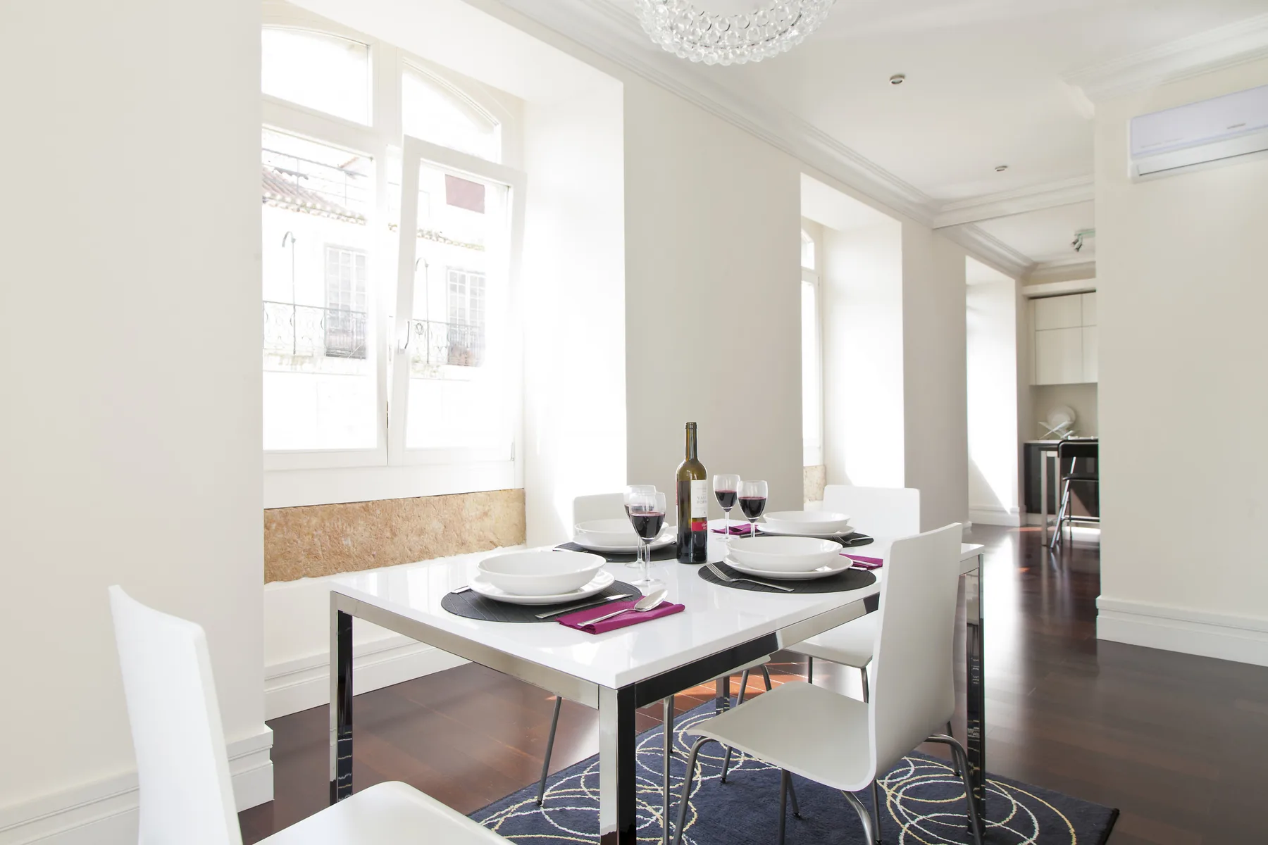 A bright dining area with a set table beside large windows.