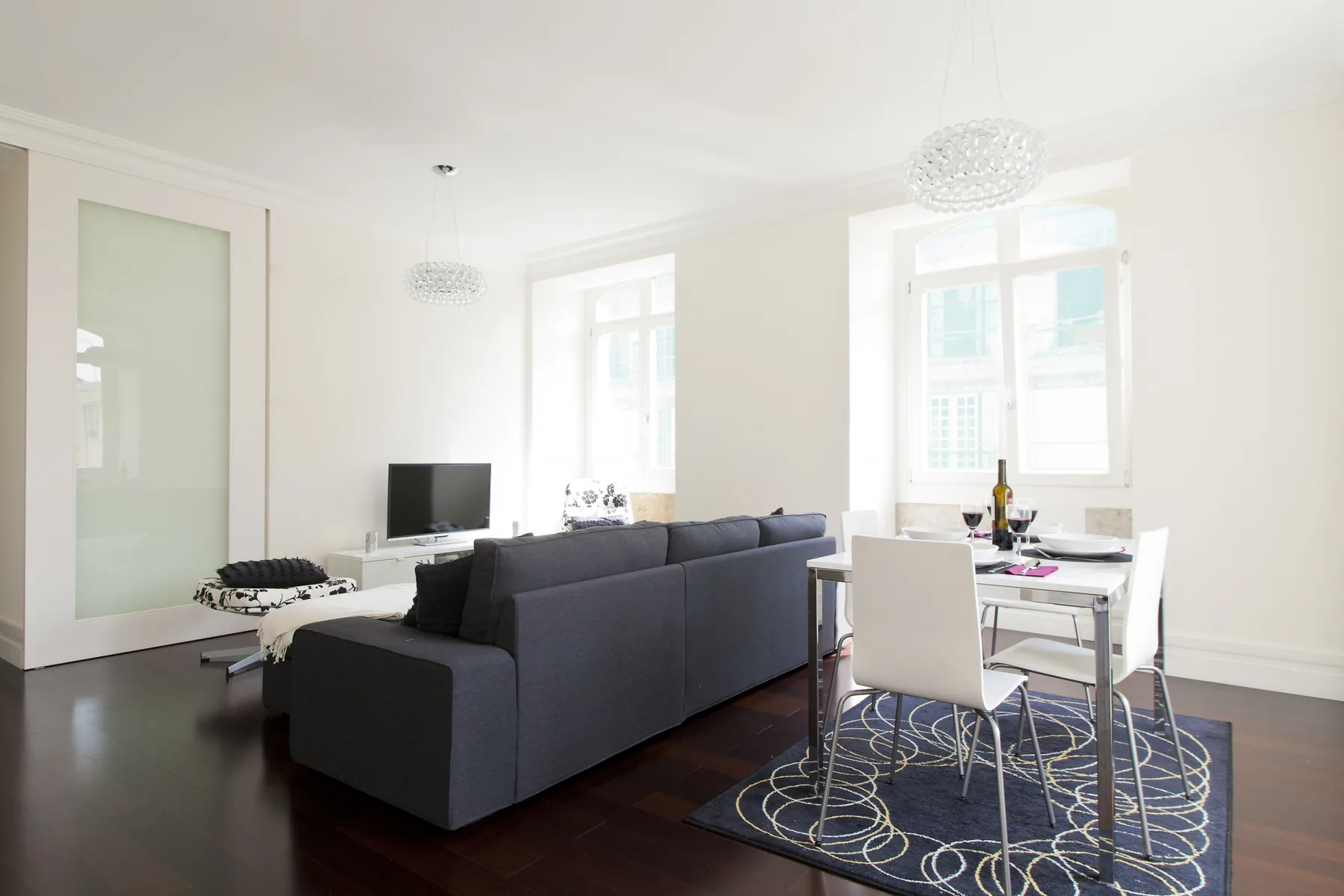 A bright living and dining area with seating, a television, and large windows.