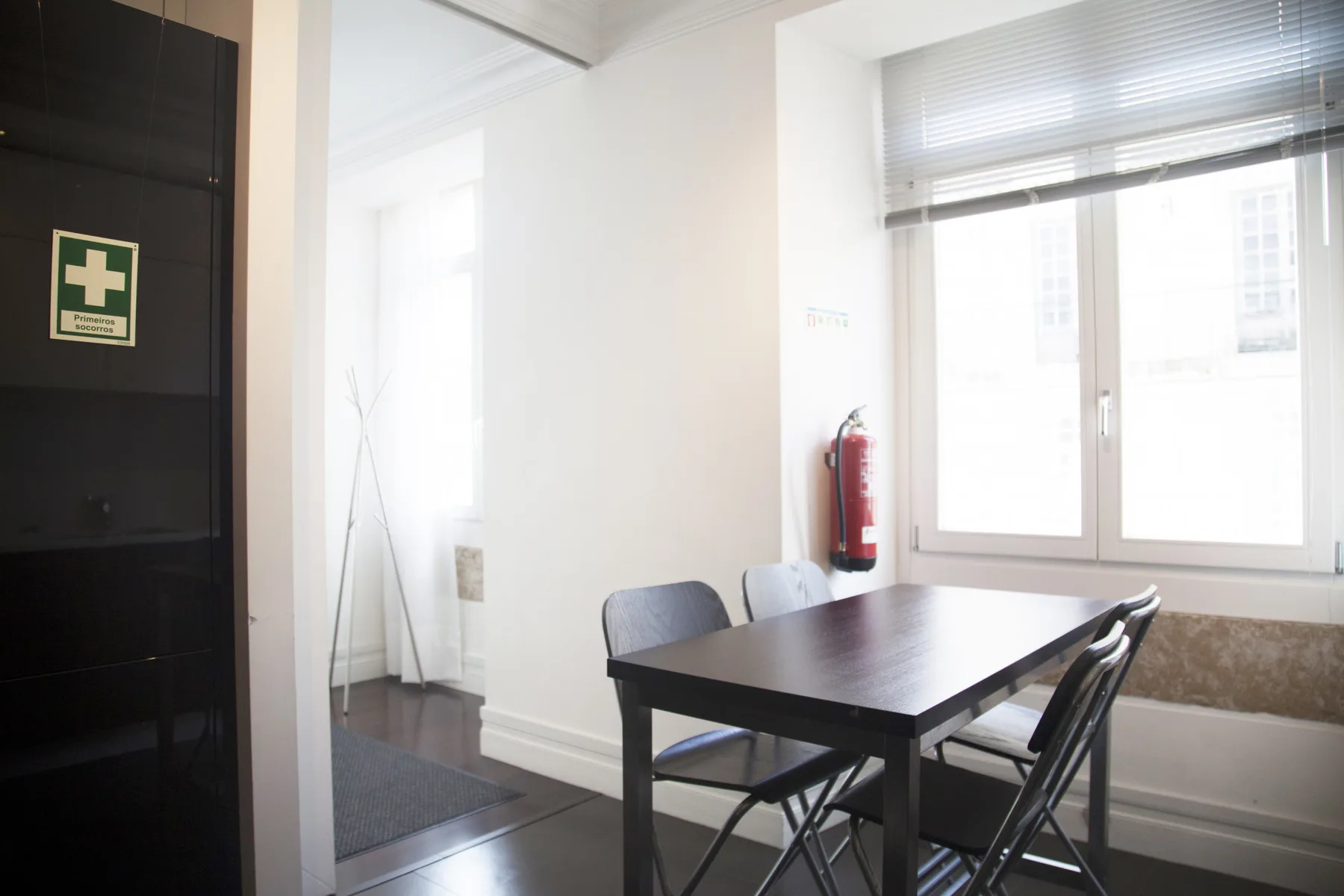 A dining area with a dark table and chairs beside a large window.