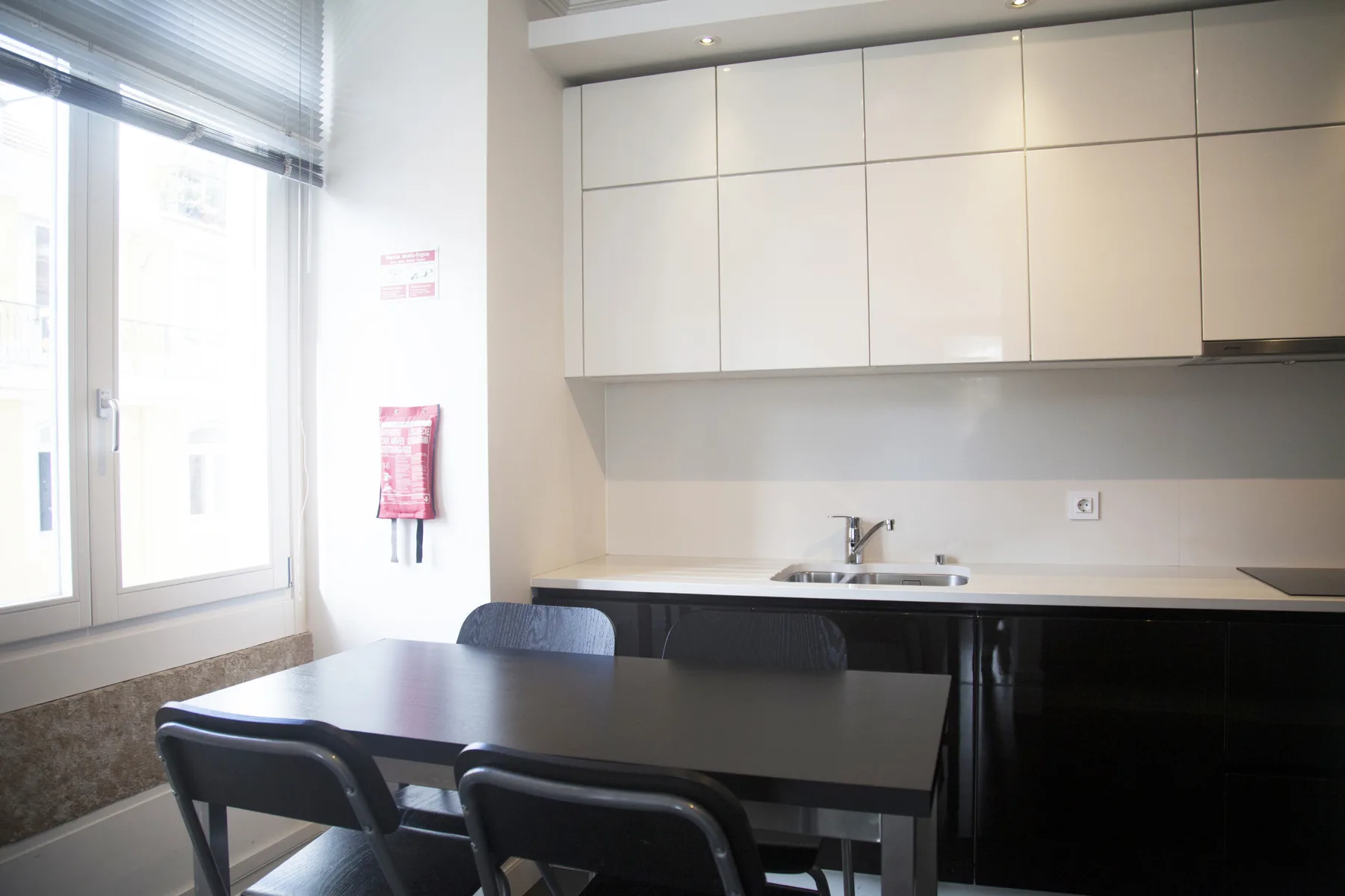 A kitchen and dining area with dark seating beside a large window.