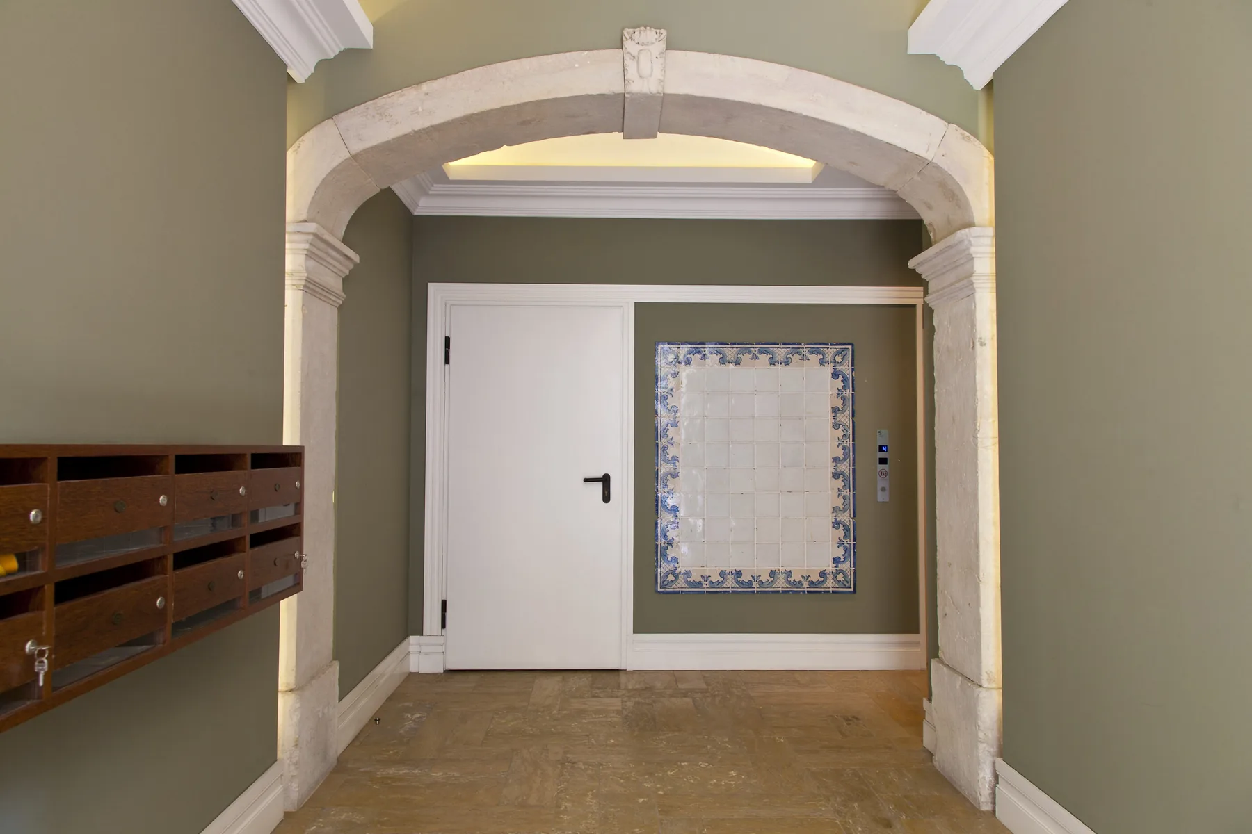 An interior hallway with a white door and a decorative tiled panel.