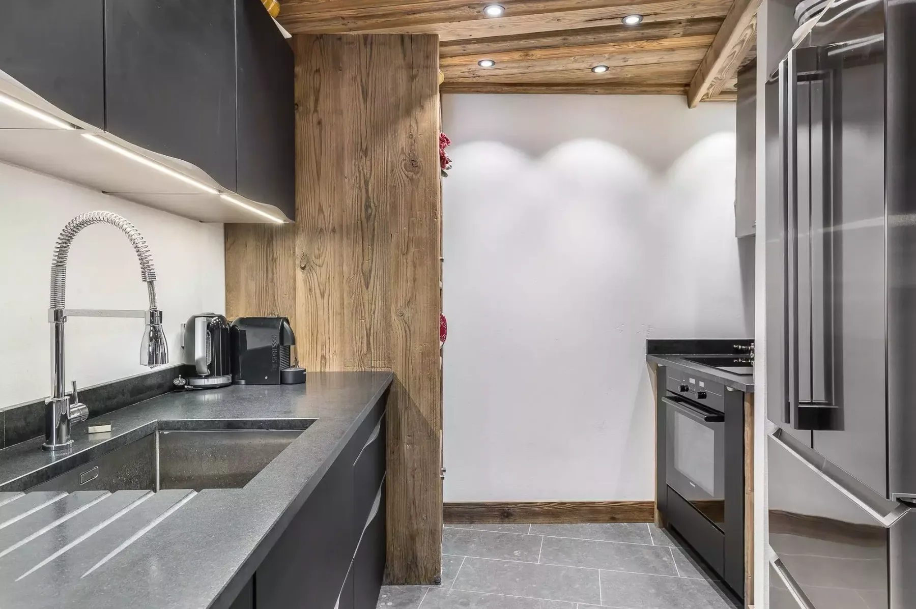 A modern kitchen with a long countertop, sink, and built-in appliances.