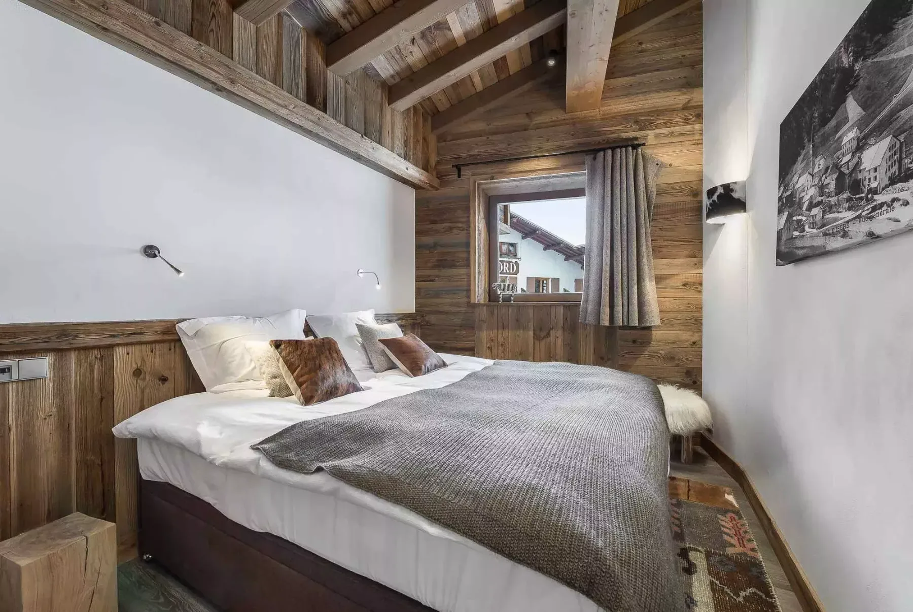 Un dormitorio con una cama bajo un techo de madera y una ventana con cortinas.