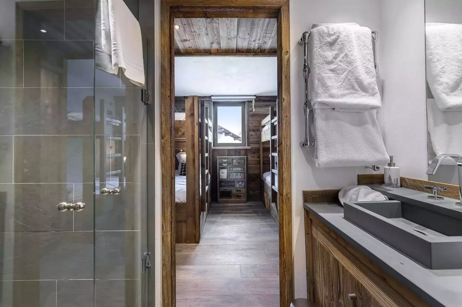 Un baño con una ducha de vidrio y un lavabo junto a una puerta abierta.