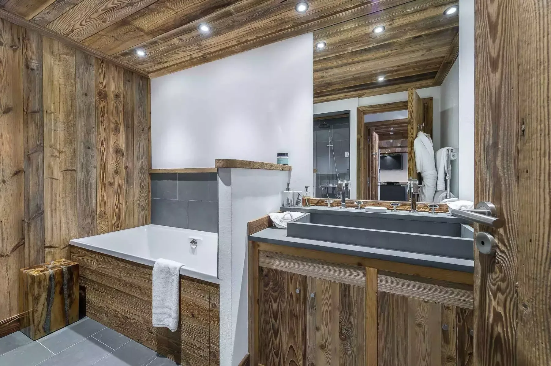 Un baño con bañera y lavabo bajo un espejo grande.