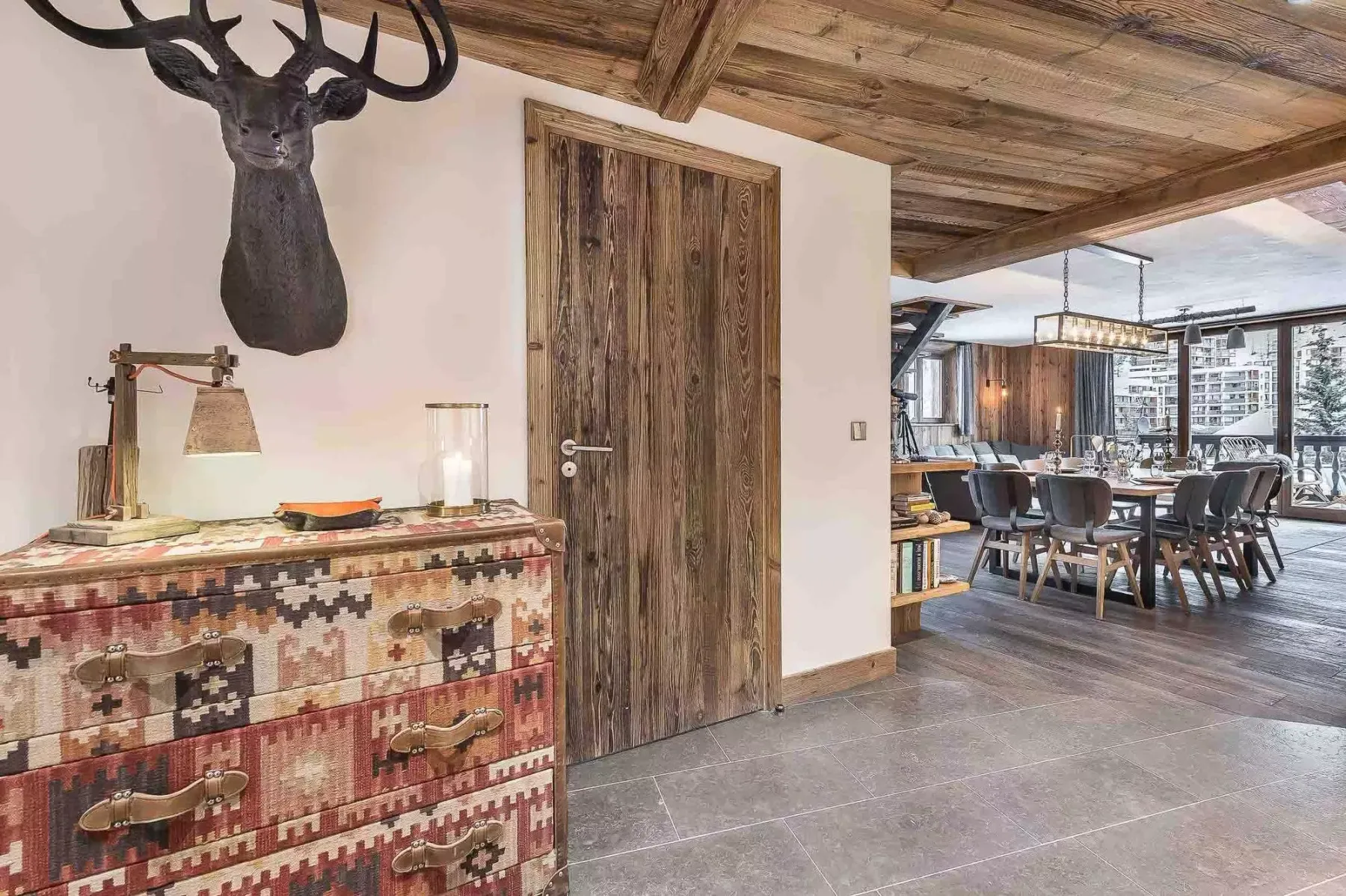 Un comedor con una mesa larga y sillas está junto a una puerta de madera rústica.
