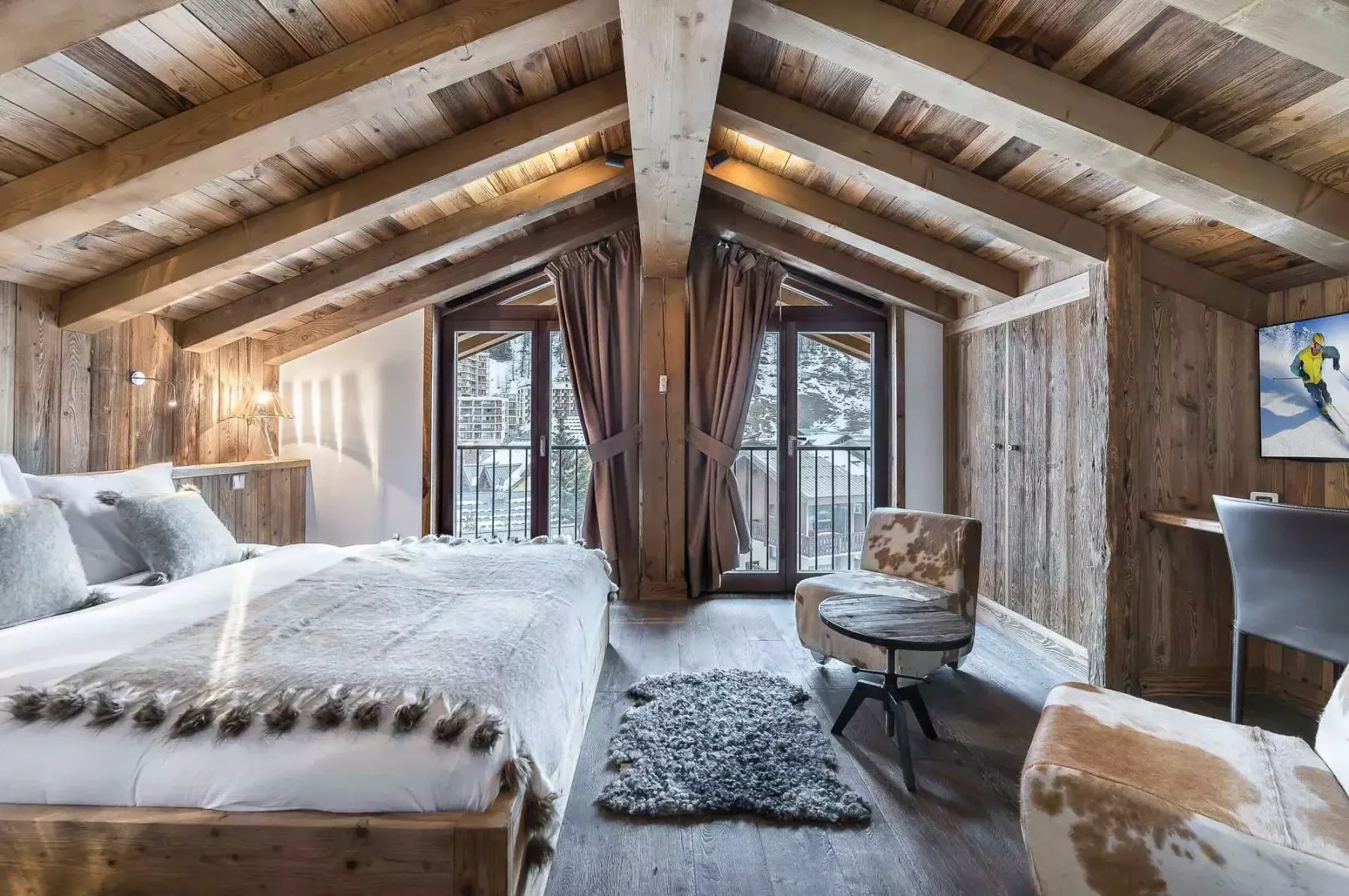Un dormitorio rústico con una cama grande y puertas de vidrio que dan a un balcón.