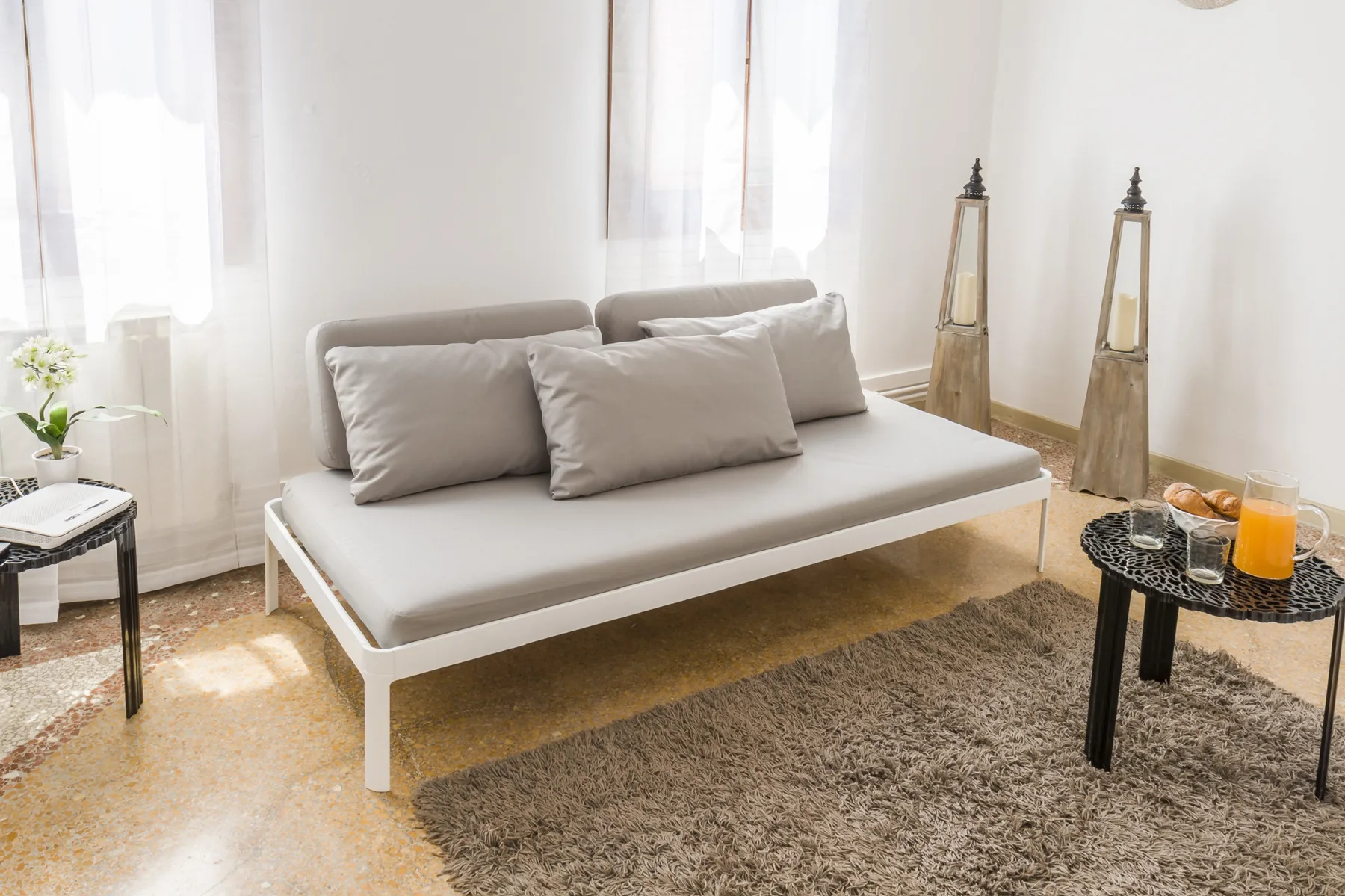 A bright living room with a light-colored sofa and a black coffee table.