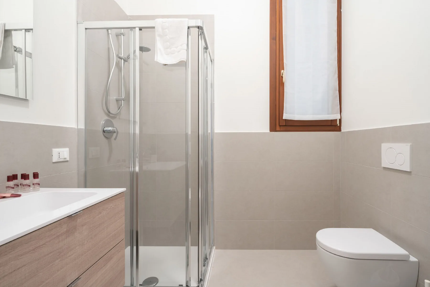 Un baño luminoso con ducha de vidrio, lavabo e inodoro.
