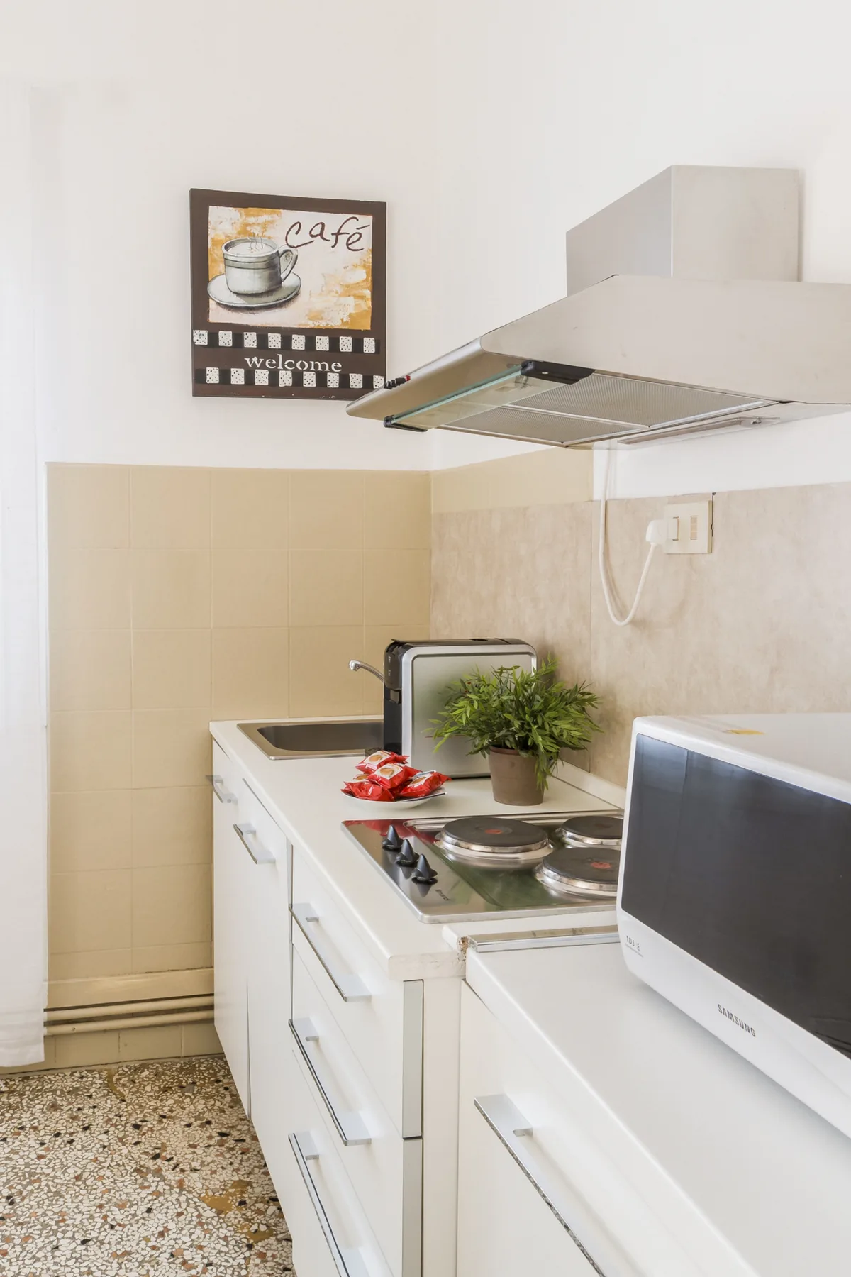 Una cocina luminosa con gabinetes blancos, una placa de cocción y un microondas sobre la encimera.