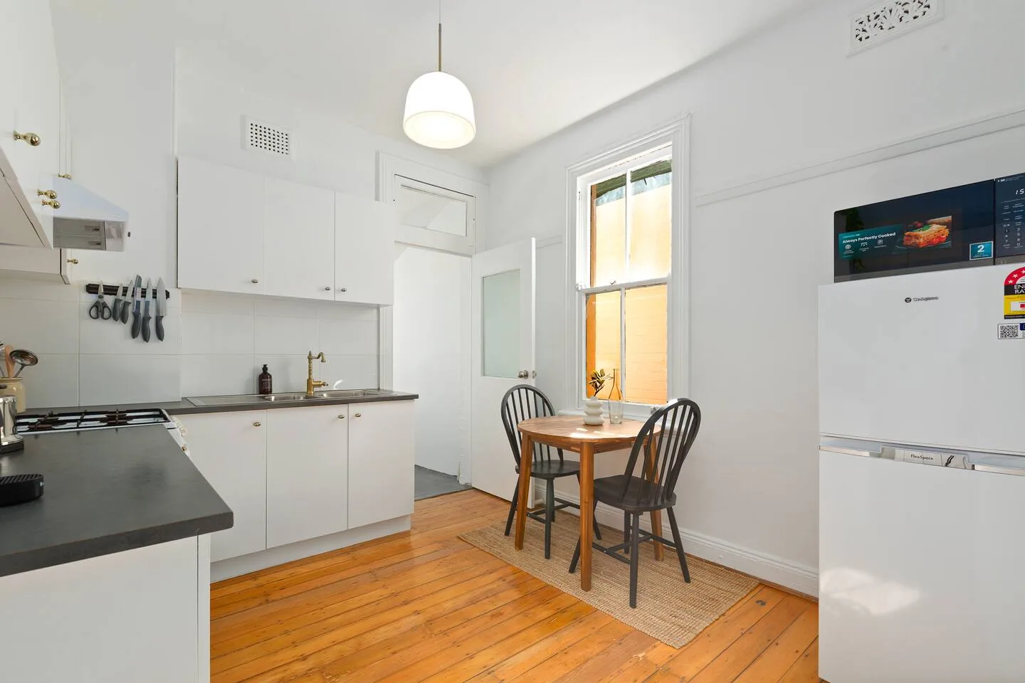 A bright kitchen and dining nook with a wooden table beside the window.