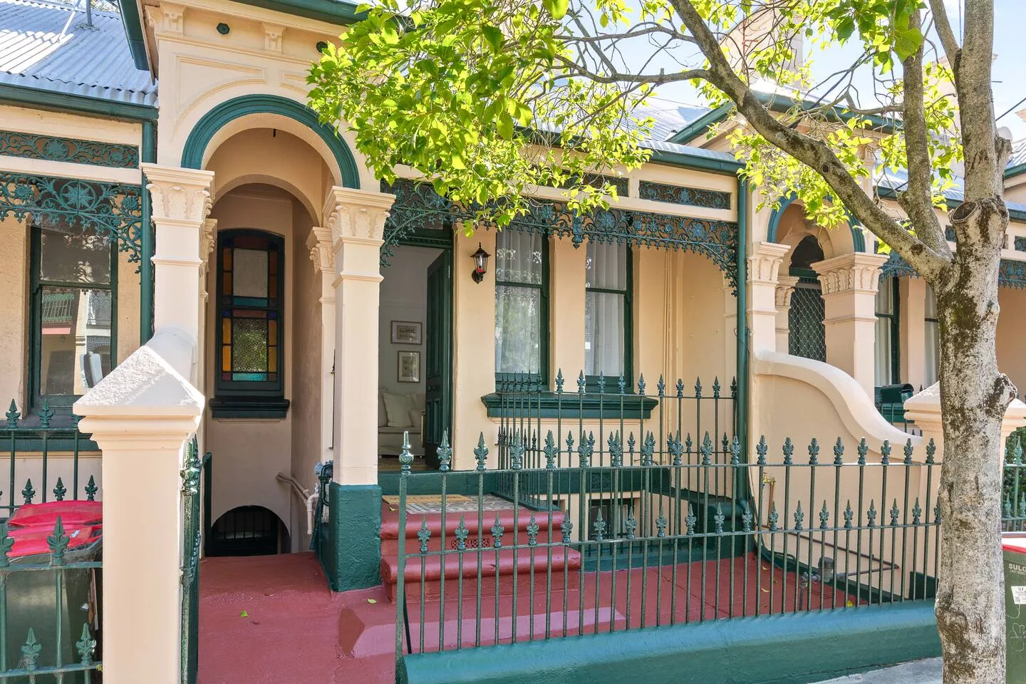 A row of ornate homes has arched entrances, decorative railings, and leafy trees.
