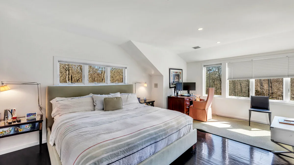 A bright bedroom with a large bed and wide windows.
