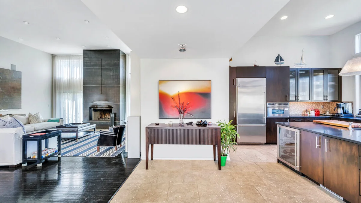 A bright open-plan living area and kitchen, with a dining table at the center.