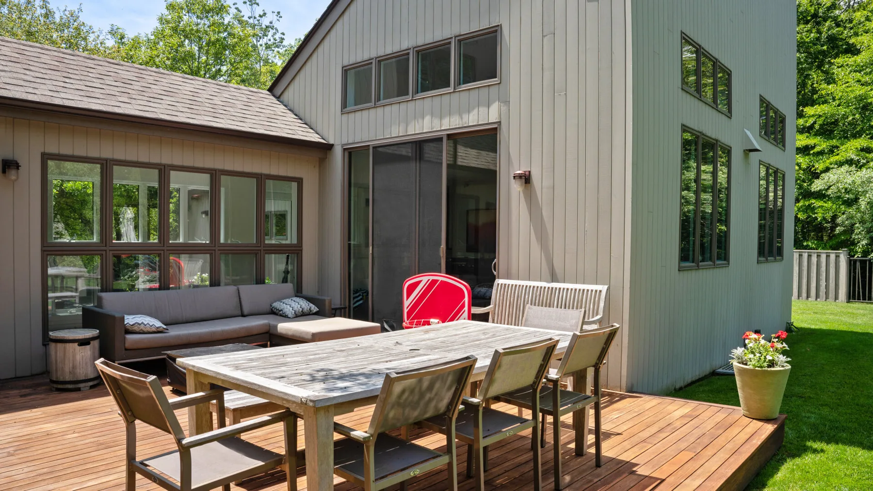 An outdoor dining area on a wooden deck beside a modern house.