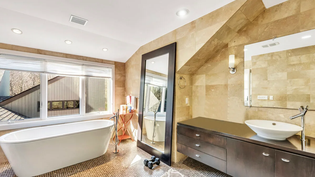 A bathroom with a bathtub, a vanity, and a large window.