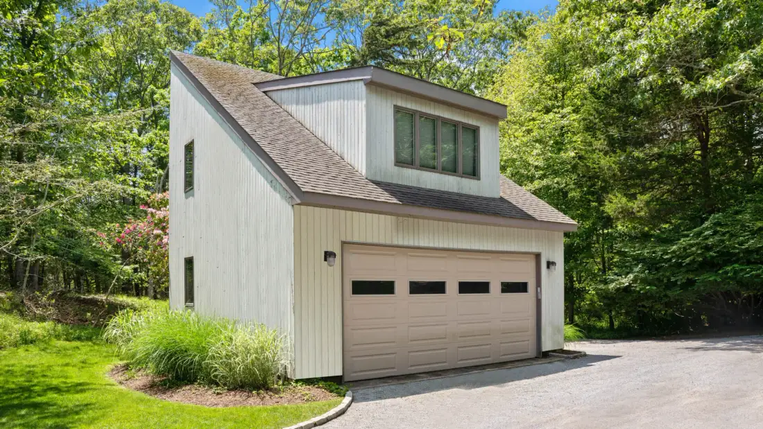 A detached garage with a light-colored exterior and a paved driveway.