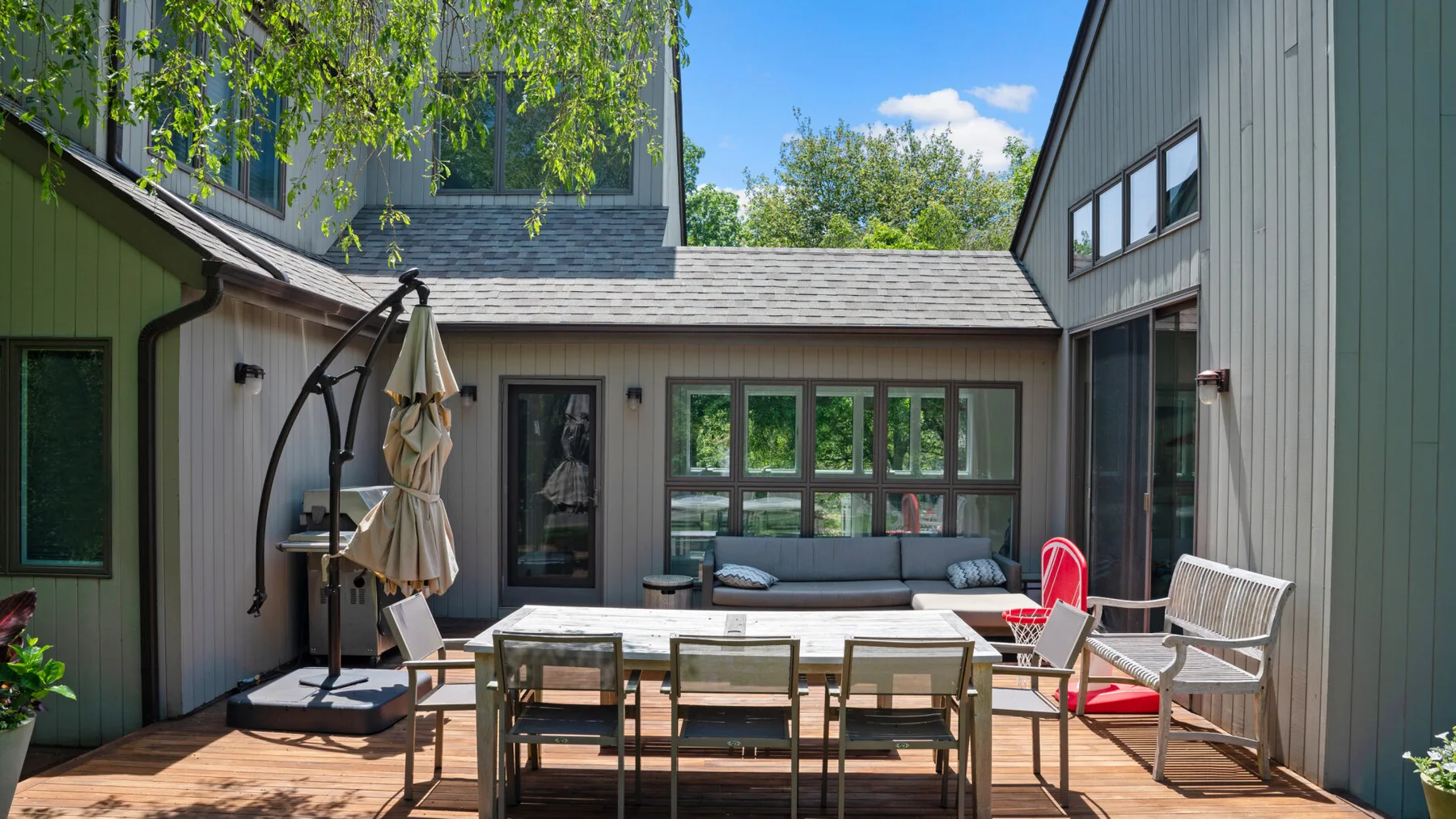 An outdoor patio with a dining table and seating beside the house.