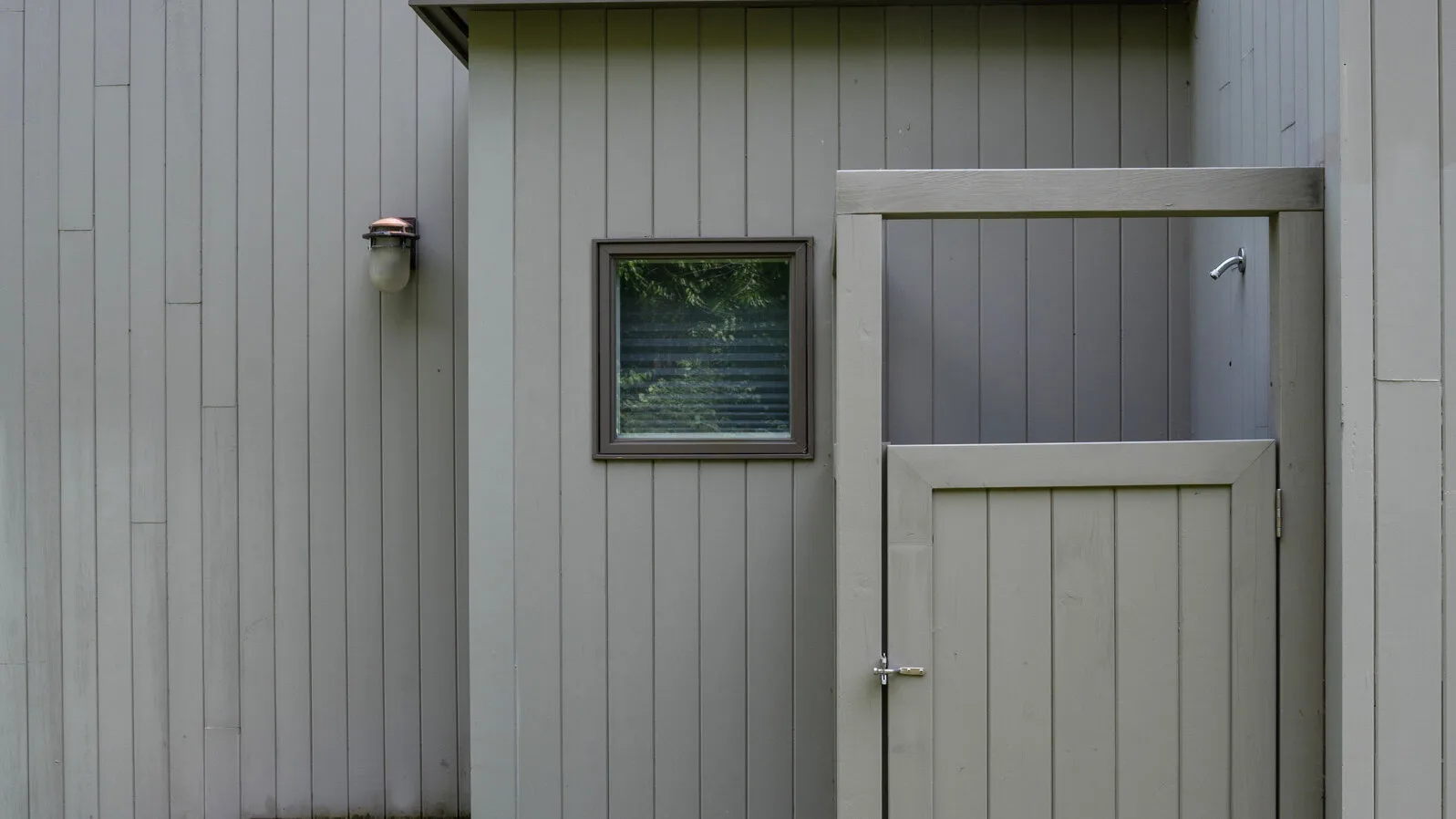 A small exterior entrance area with a partially open gate and a window.
