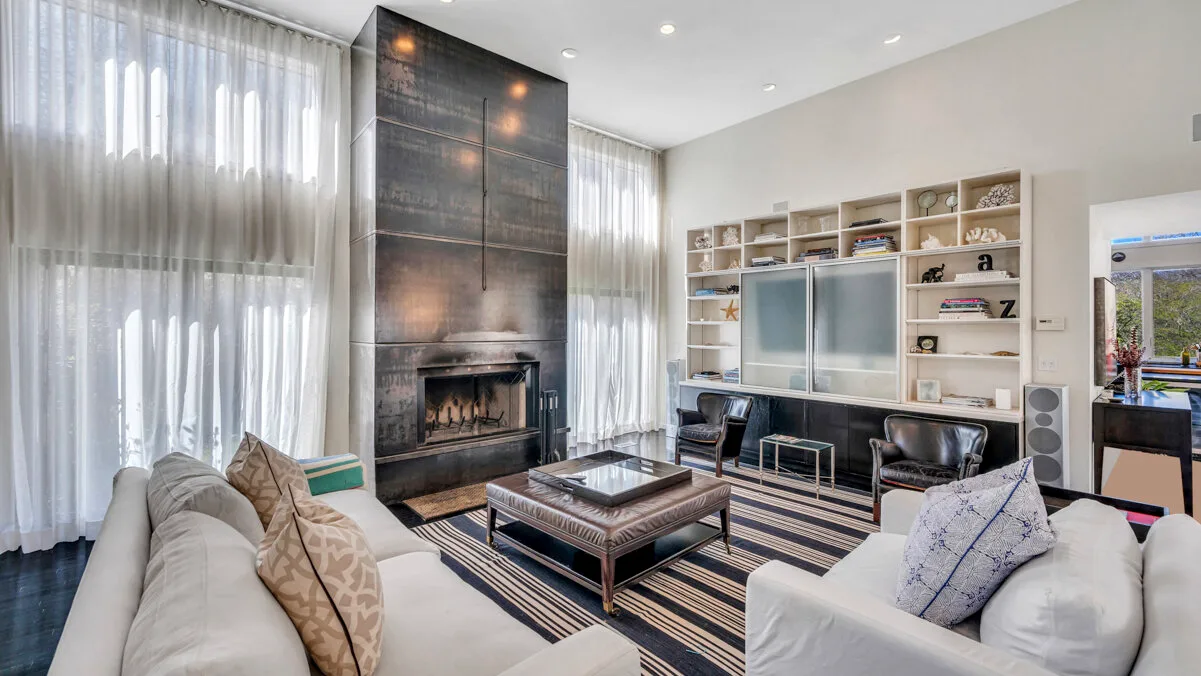 A bright living room with seating, a fireplace, and built-in shelving.