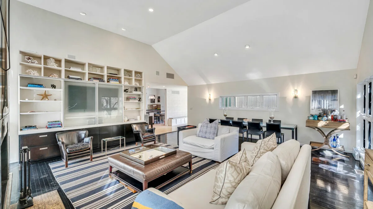 A bright living room with seating, a coffee table, and built-in shelving.
