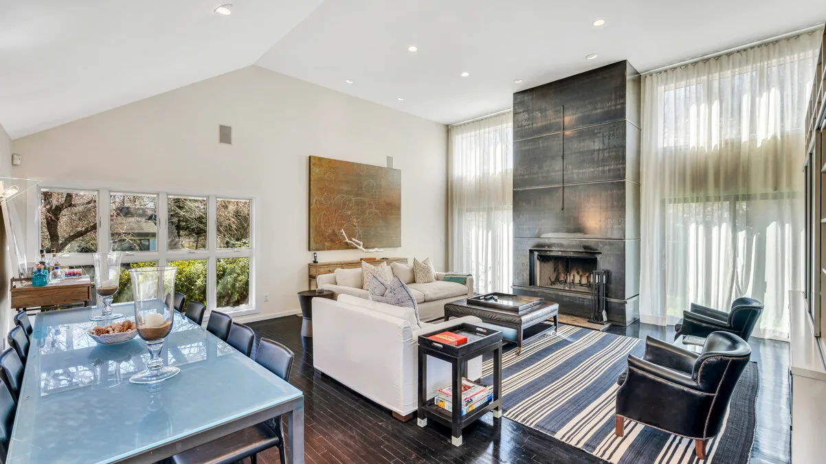 A bright living room with seating arranged around a coffee table and fireplace.