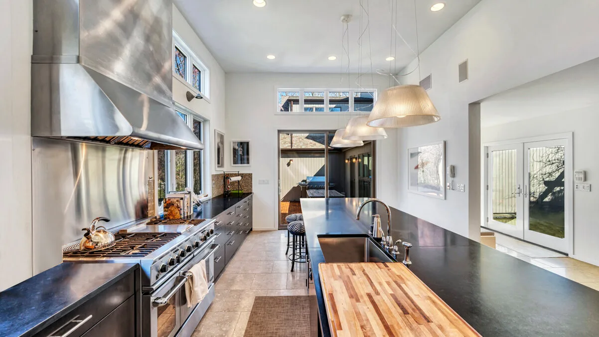 A bright modern kitchen with a long island and stainless steel cooking range.